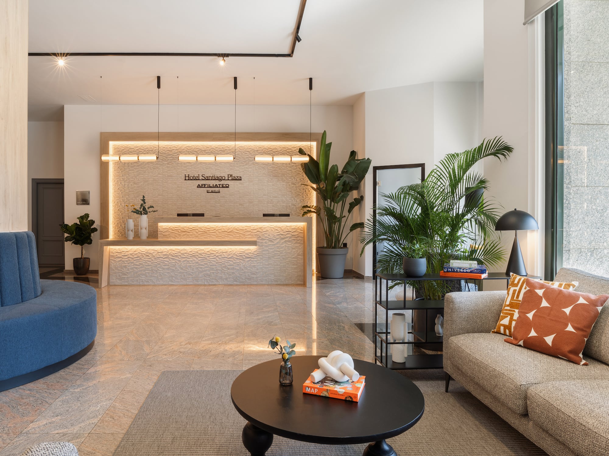 Lobby Hotel Santiago Plaza: Recepción moderna, mostrador iluminado, sofás, plantas.