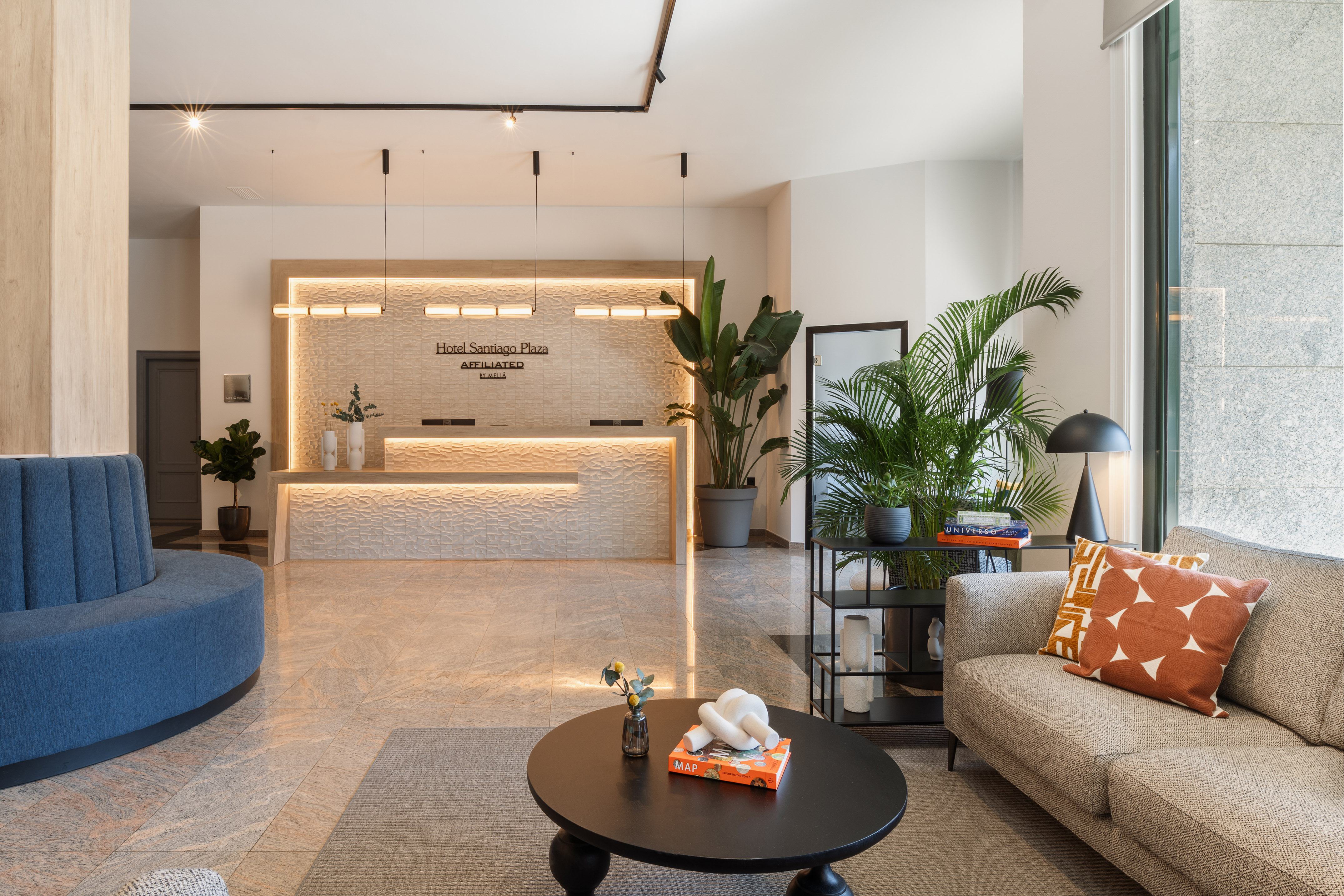 Lobby Hotel Santiago Plaza: Recepción moderna, mostrador iluminado, sofás, plantas.