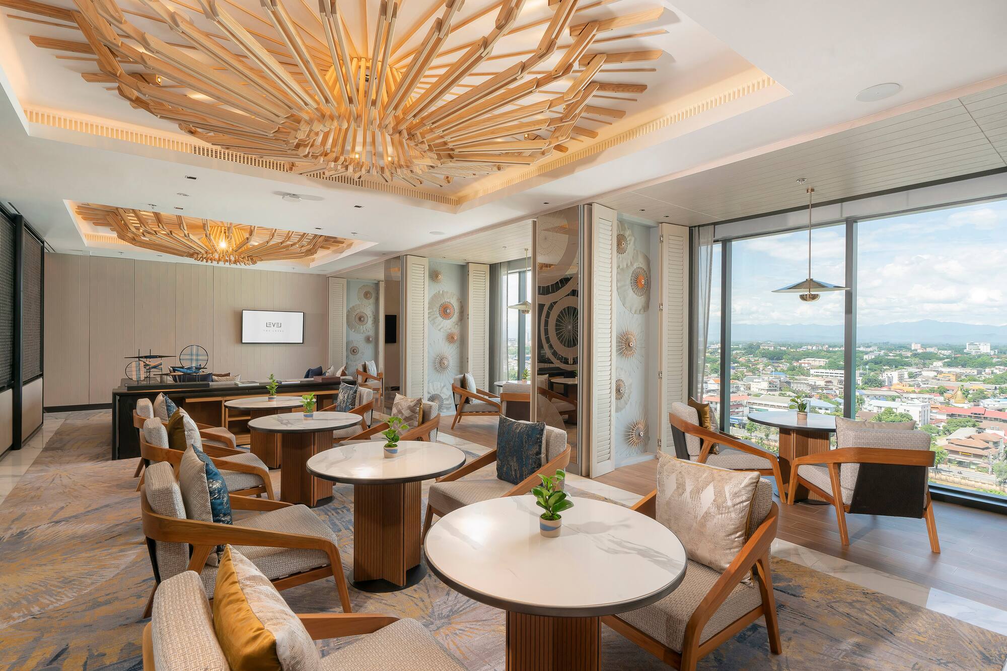 Executive lounge with city view, ornate wooden ceiling, and modern seating.