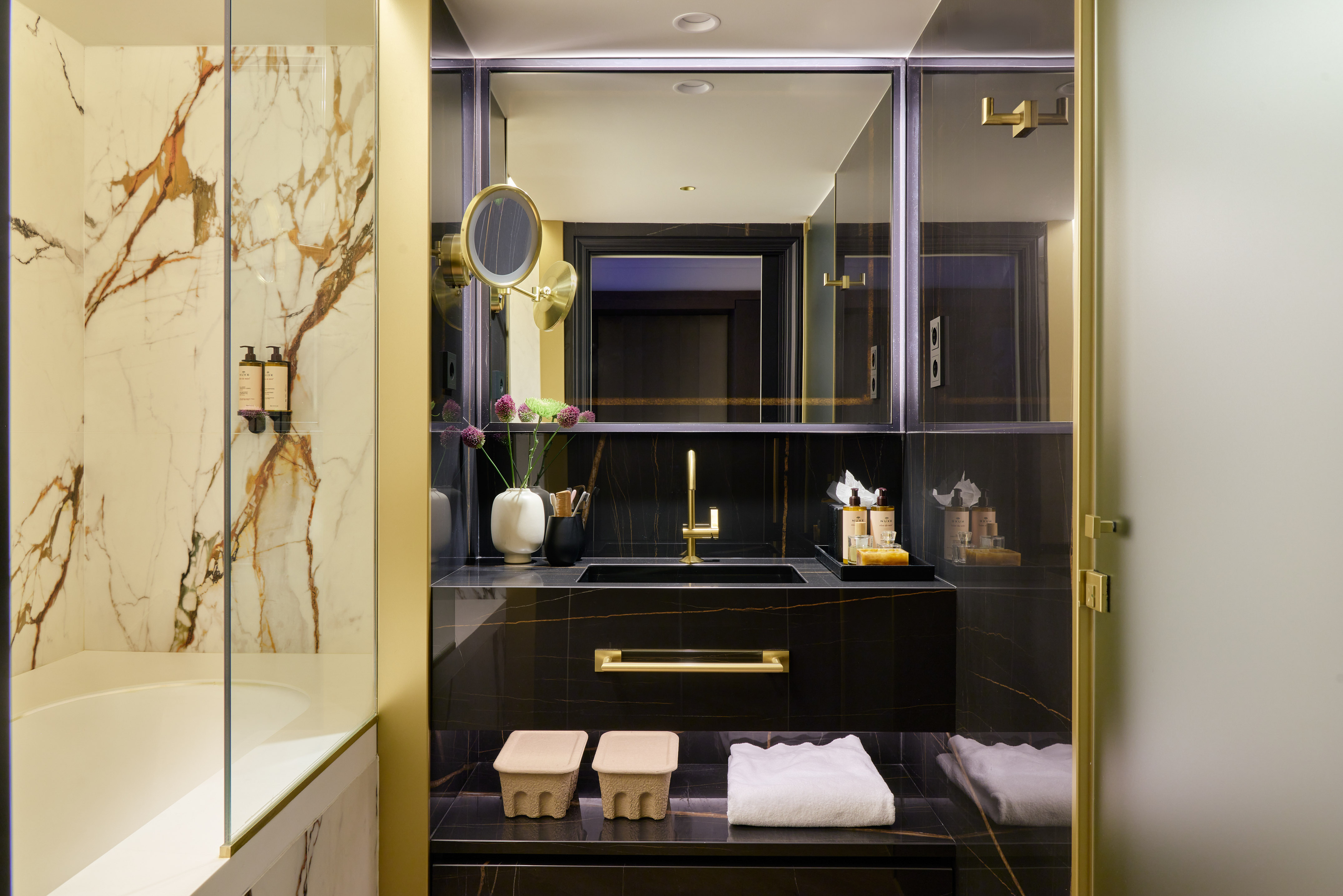 Luxury hotel bathroom, black marble vanity, gold accents, marble shower.