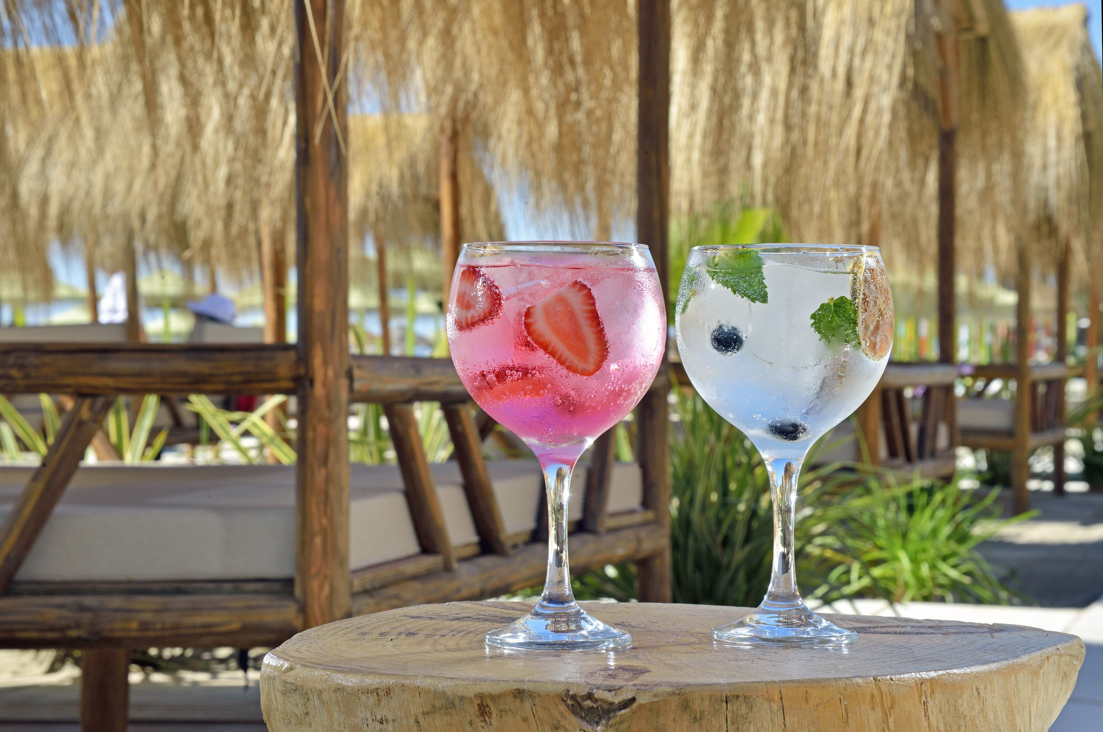 Strawberry and blueberry cocktails on wood table, beach bar background.