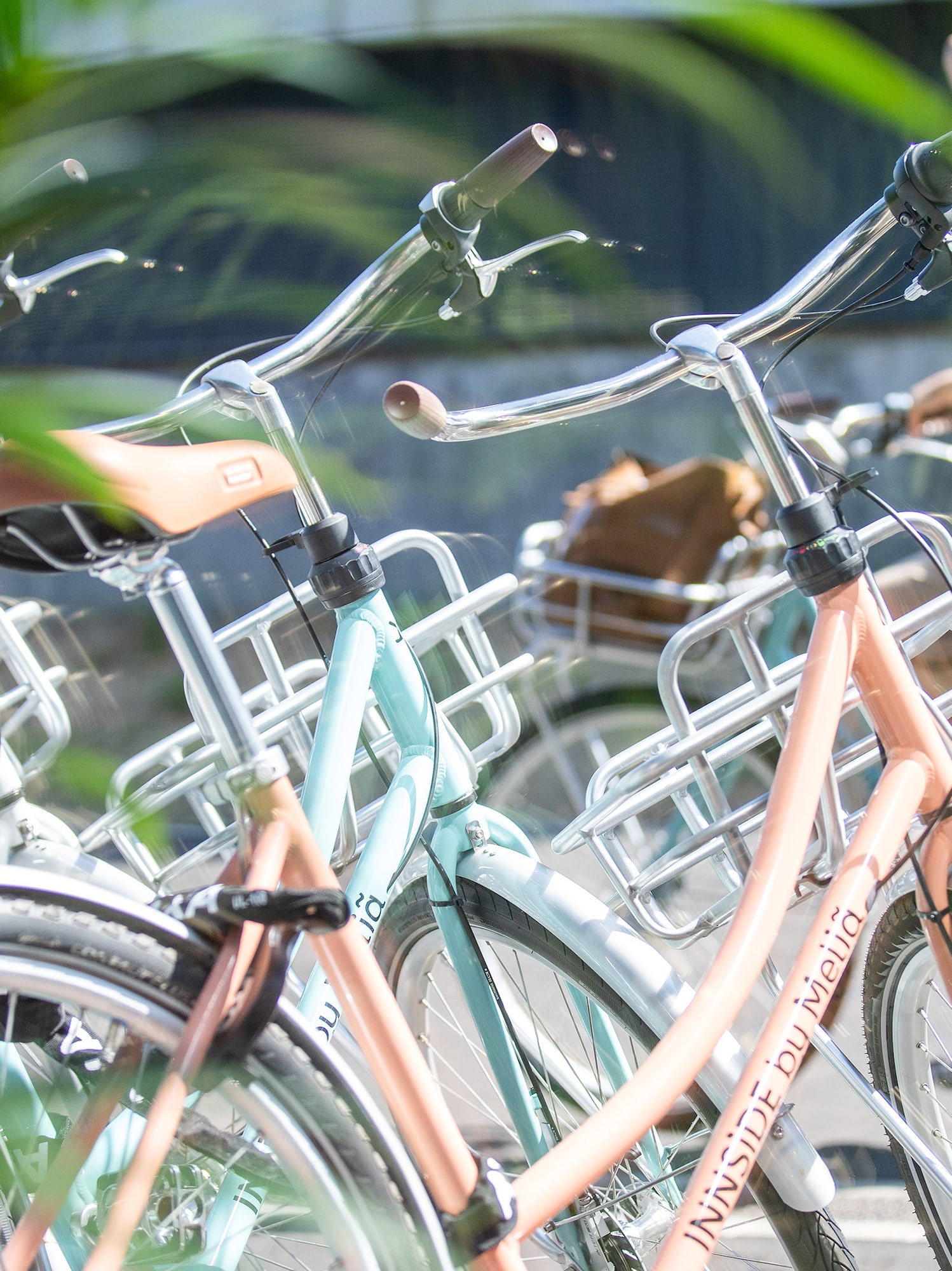 Pastel bikes with front baskets at a Meliá hotel, woman nearby.