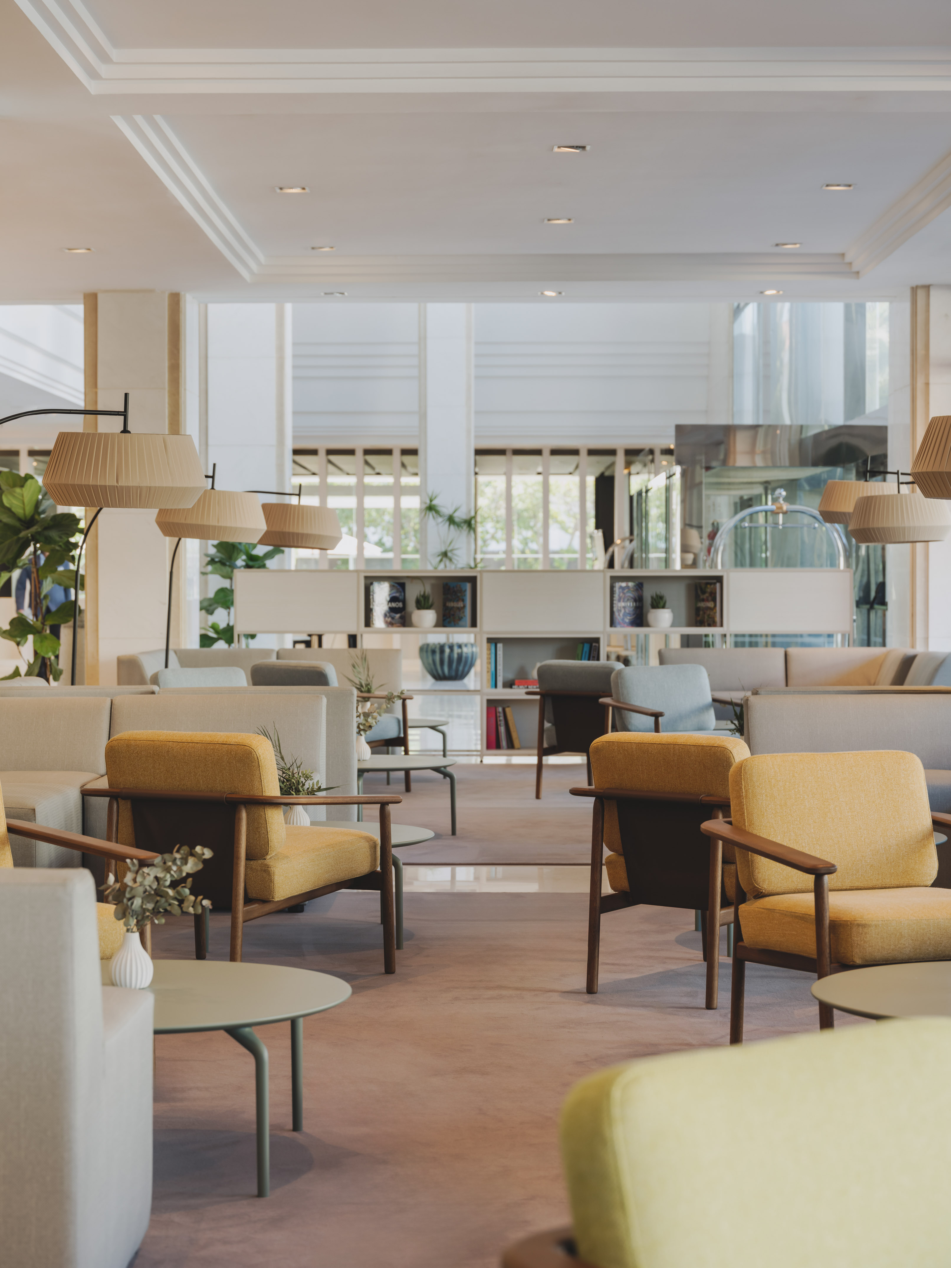Inviting hotel lounge with mustard armchairs, gray sofas, and modern floor lamps.