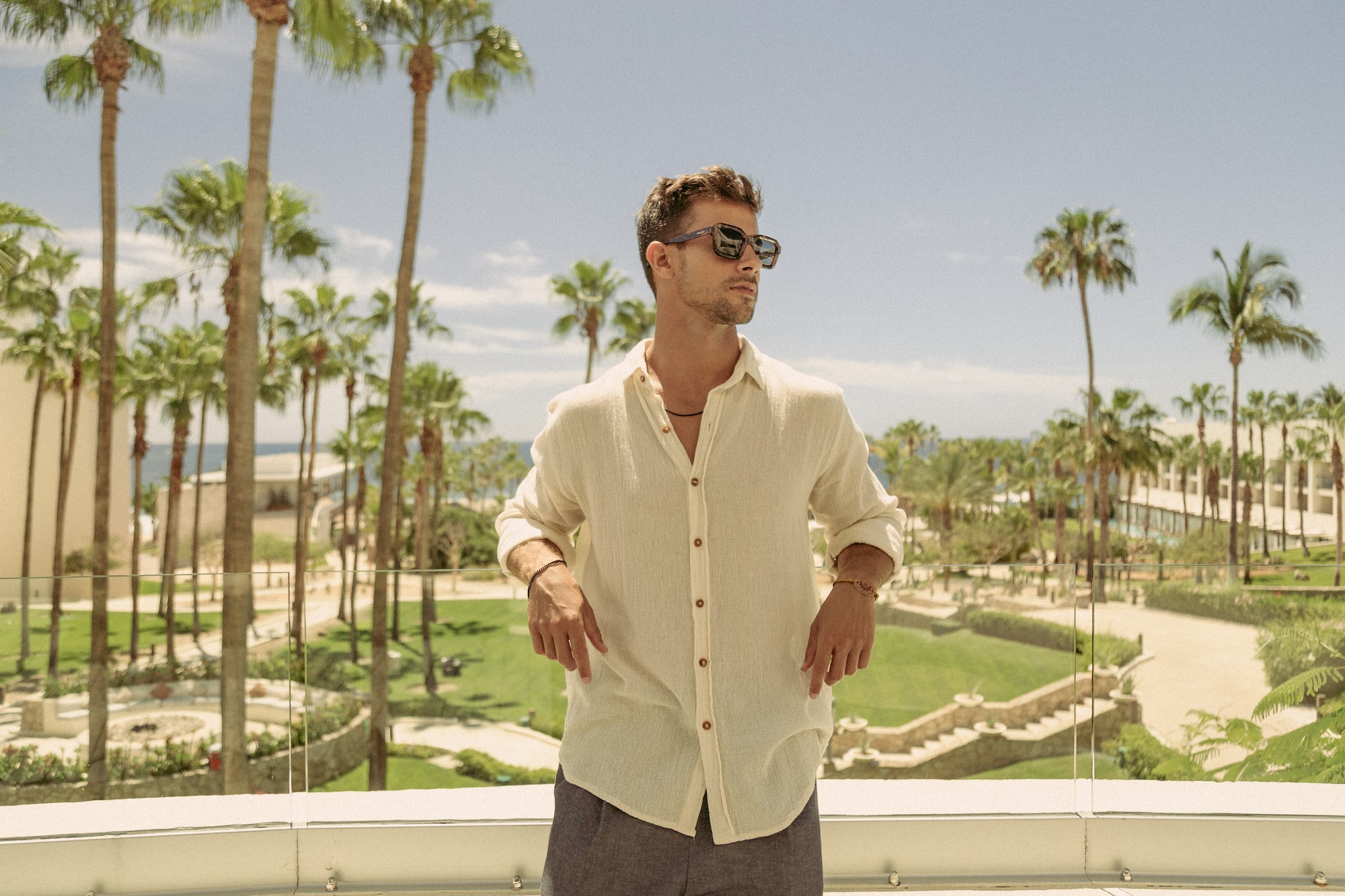 a man standing on a balcony with palm trees