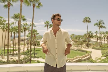 a man standing on a balcony with palm trees