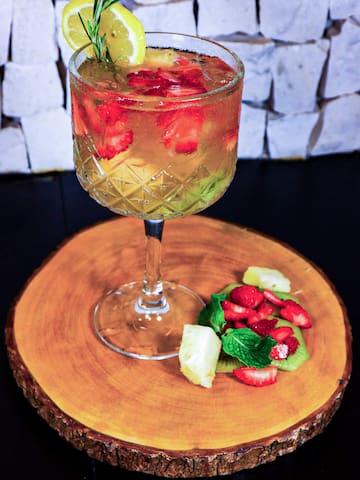 a glass of drink with fruit on a wood plate