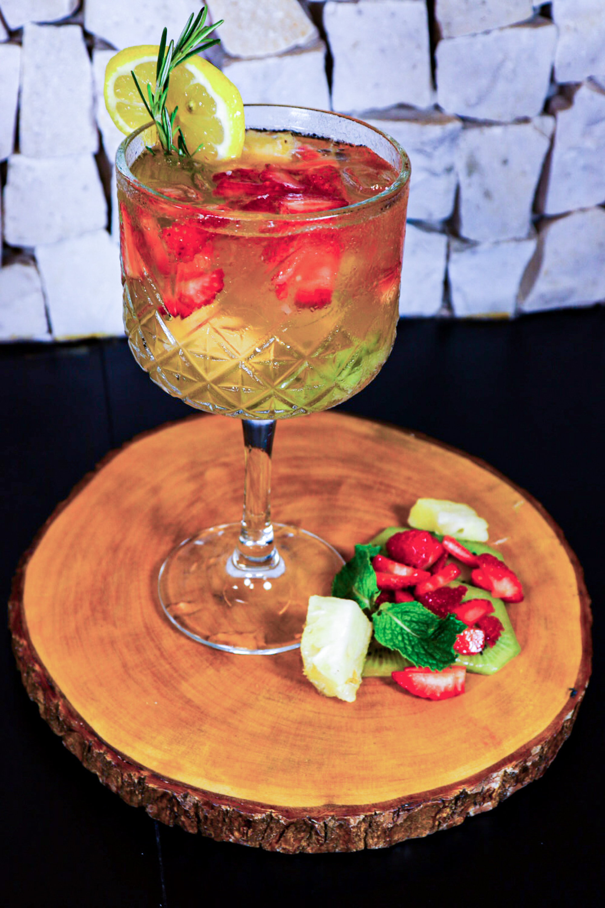 a glass of drink with fruit on a wood plate