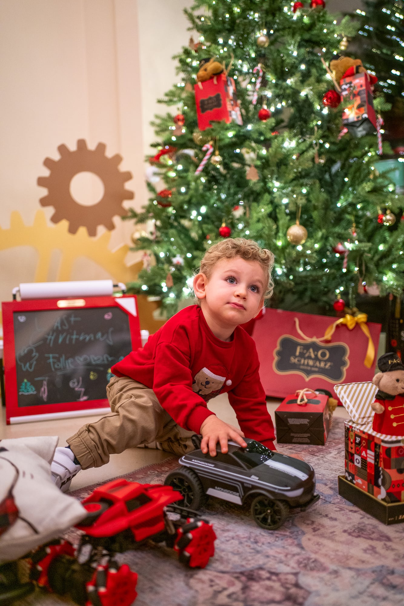 a child playing with a toy car in front of a christmas tree