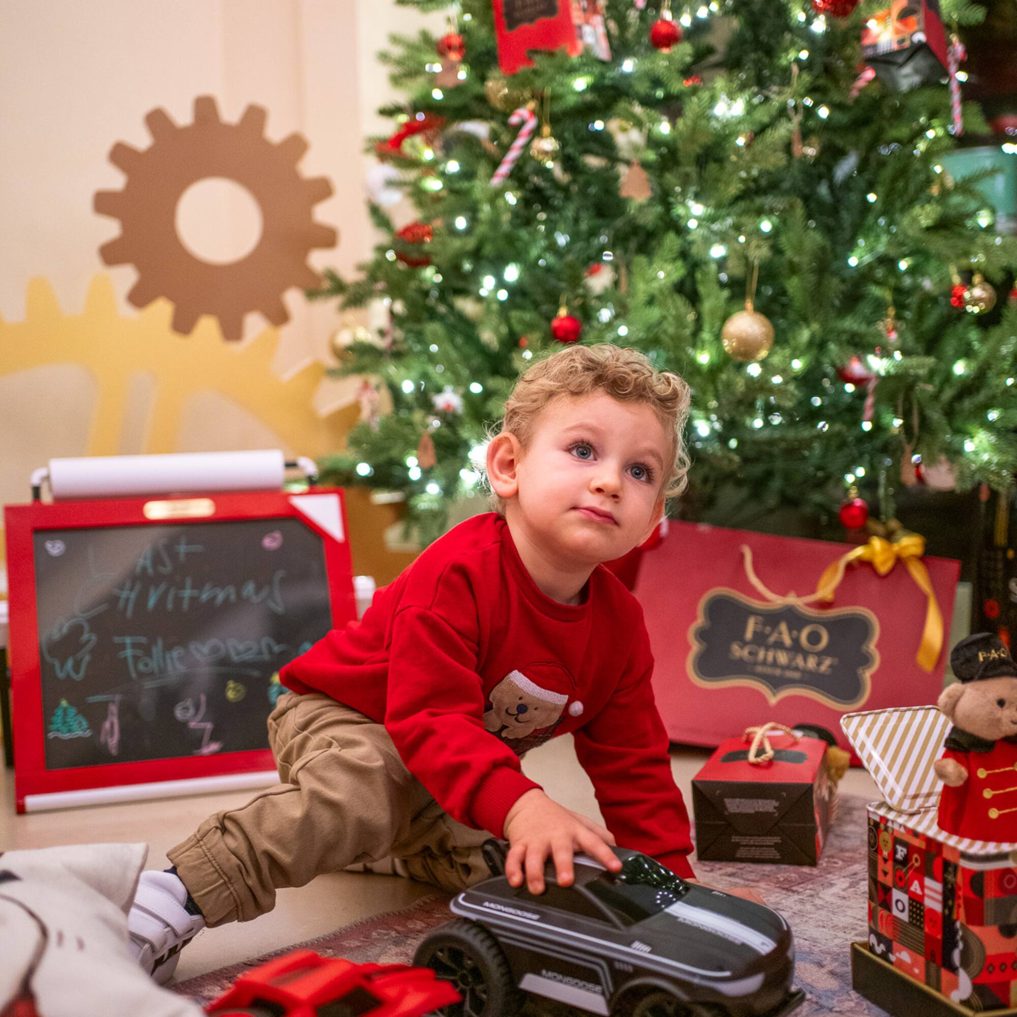 a child playing with a toy car in front of a christmas tree
