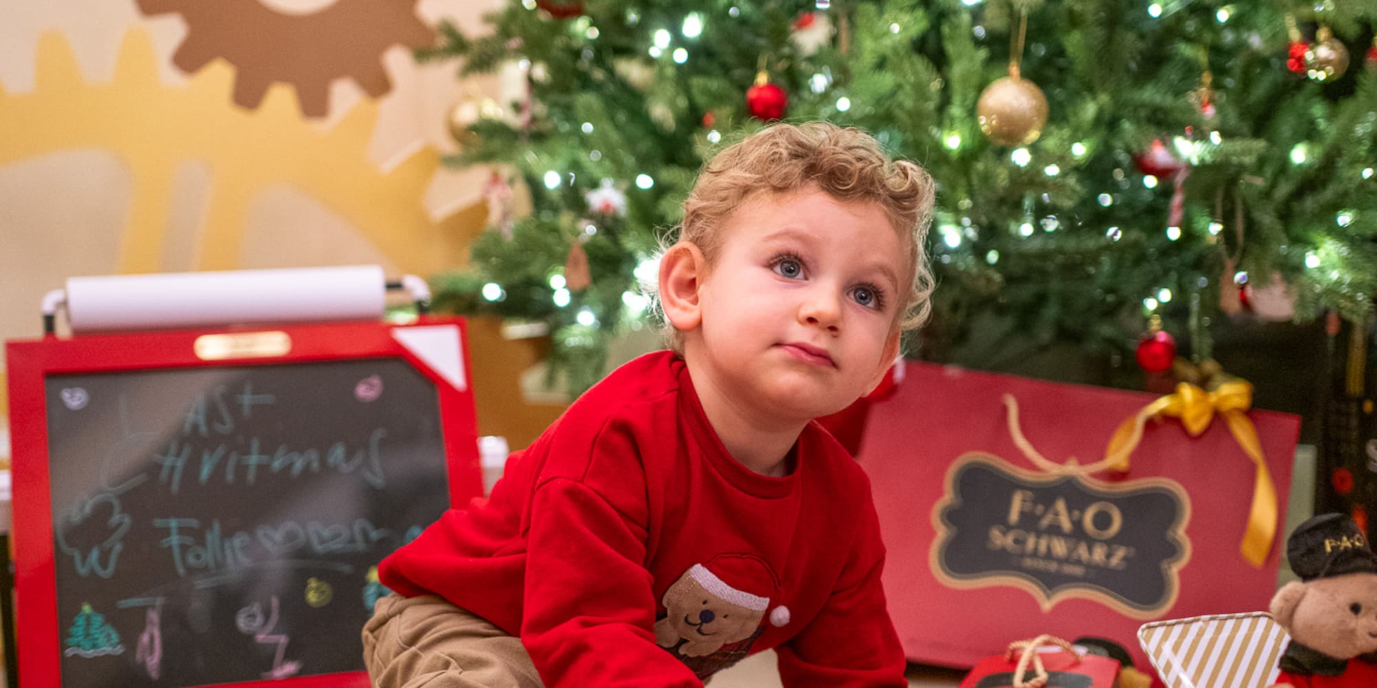 a child playing with a toy car in front of a christmas tree