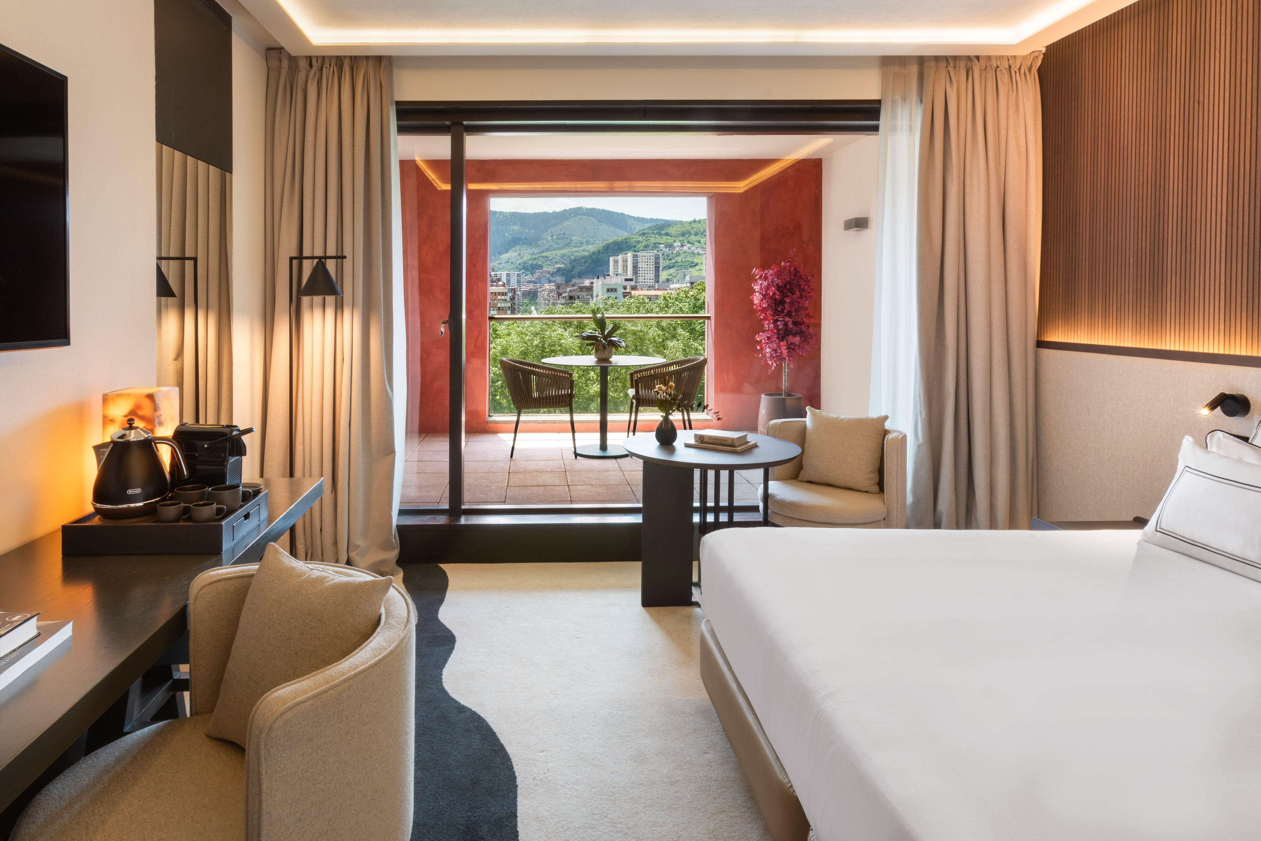 Luxury hotel room with balcony, mountain view, and modern decor.