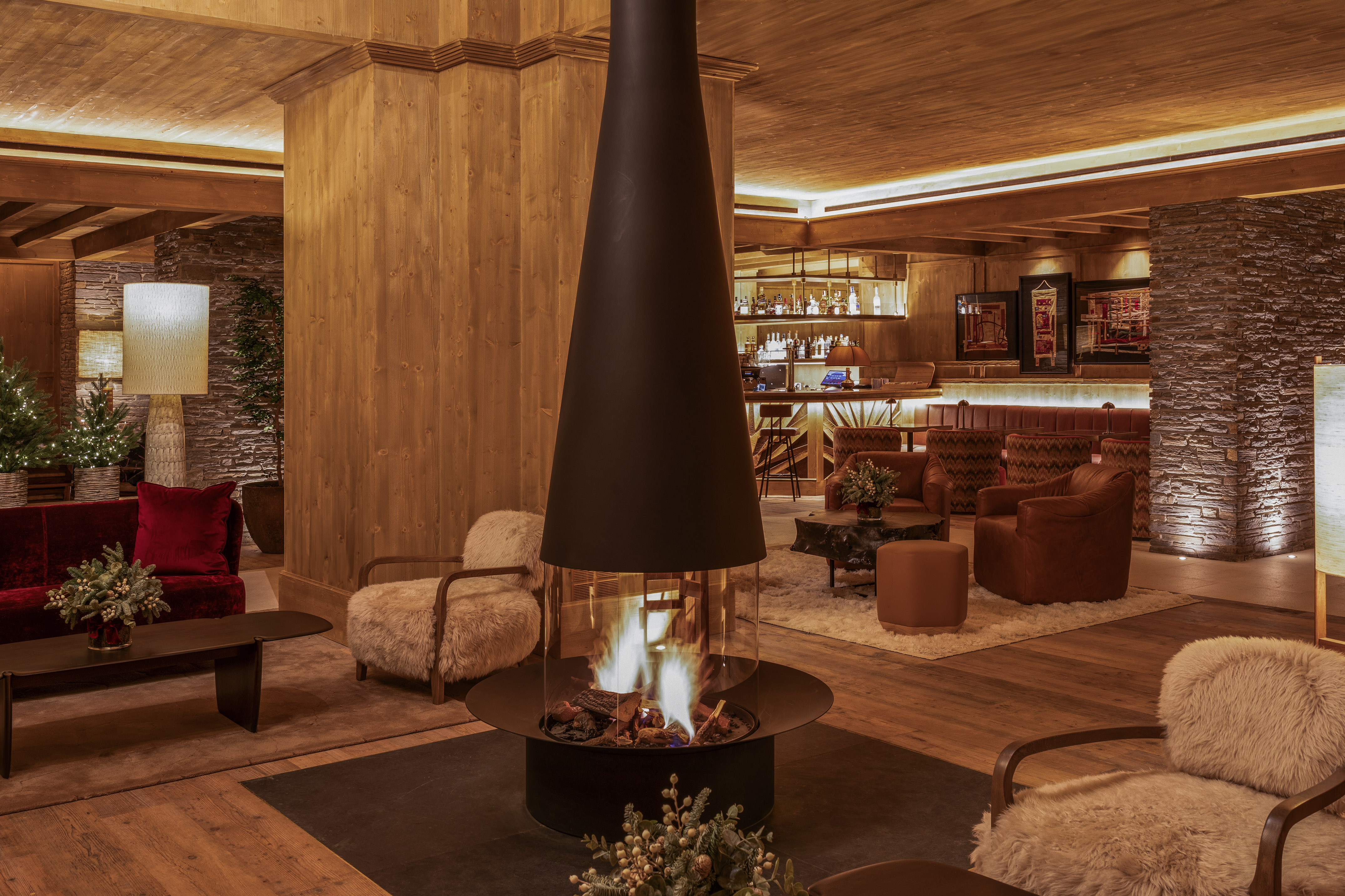 Cozy ski lounge with modern fireplace, wooden decor, plush seating, and bar.