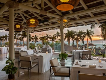 a restaurant with tables and chairs and a view of the ocean