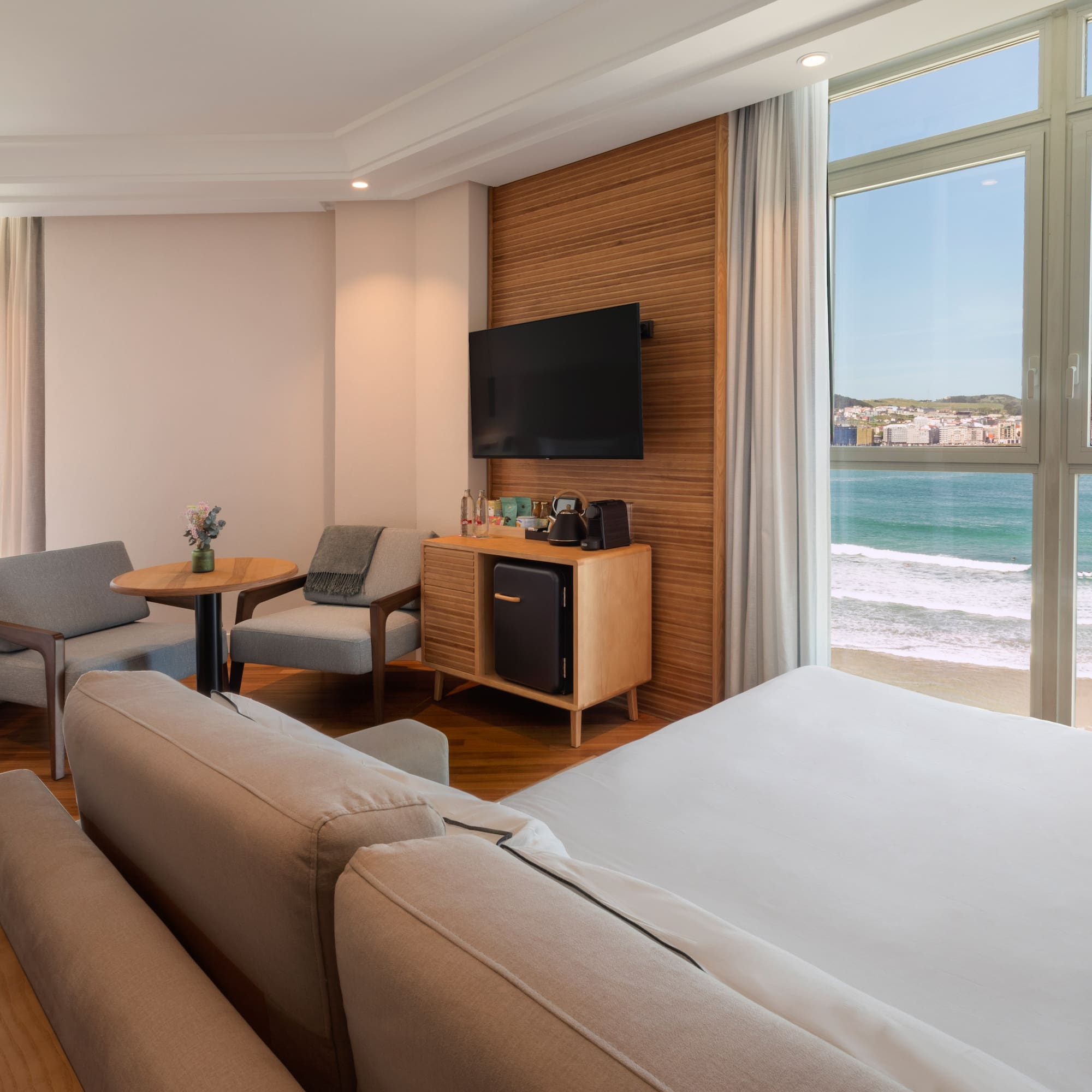 a room with a large bed and a television and chairs