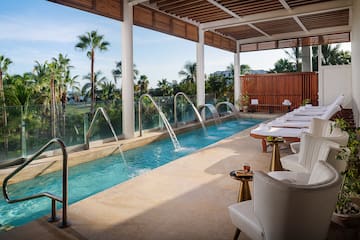 a pool with water jets and chairs in a room with a pool and chairs