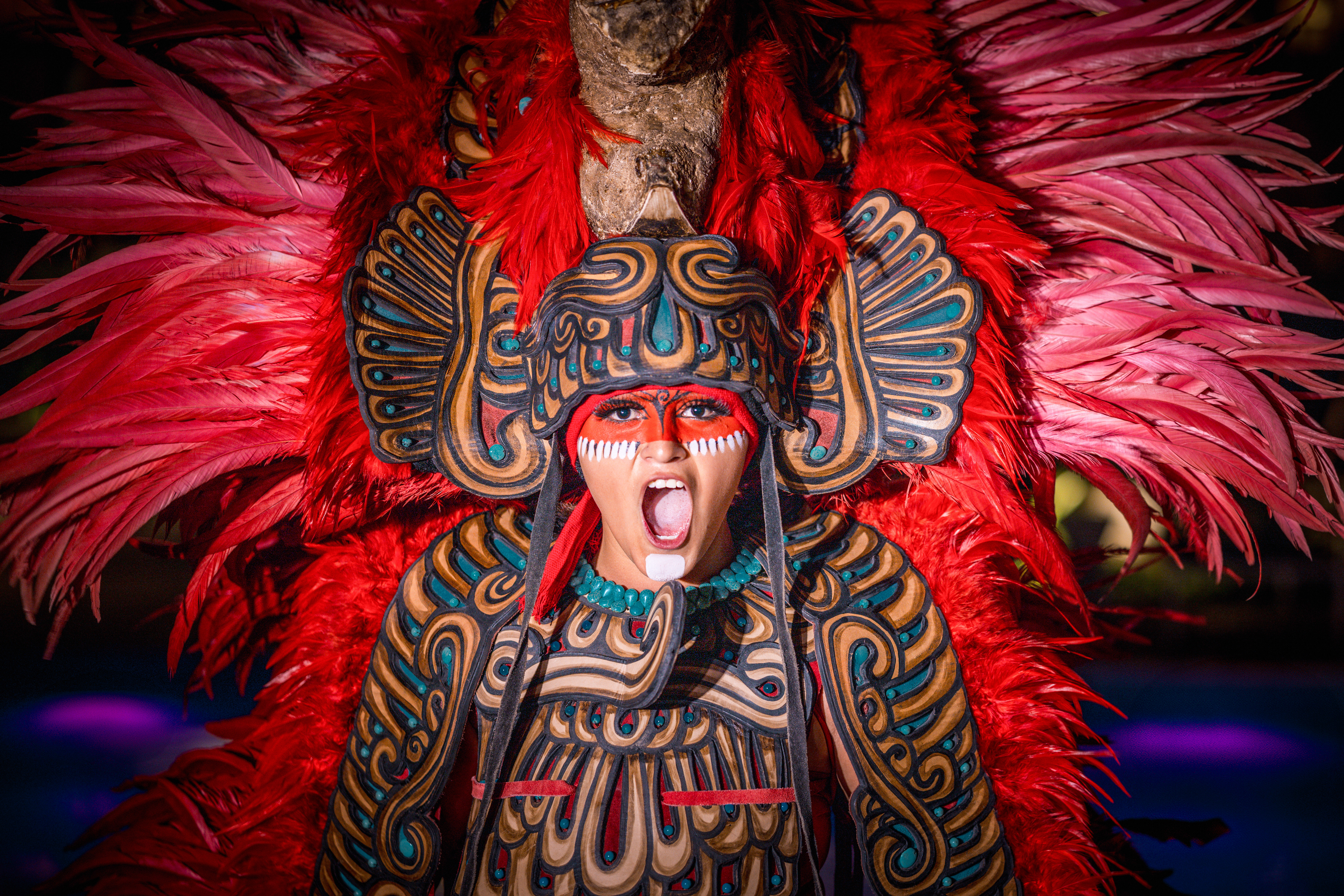Vibrant red feathered costume, intricate headdress, tribal face paint.