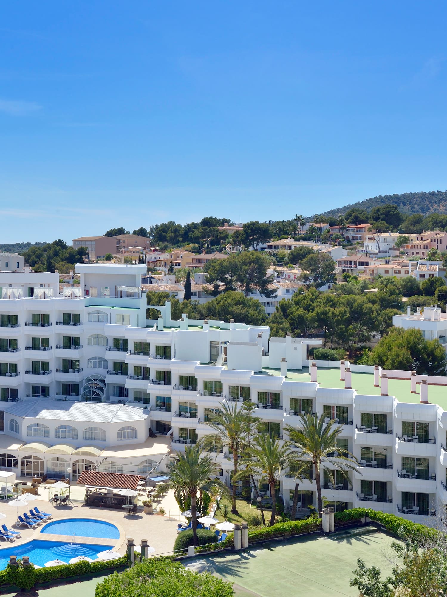 a large white building with a pool and trees in the background