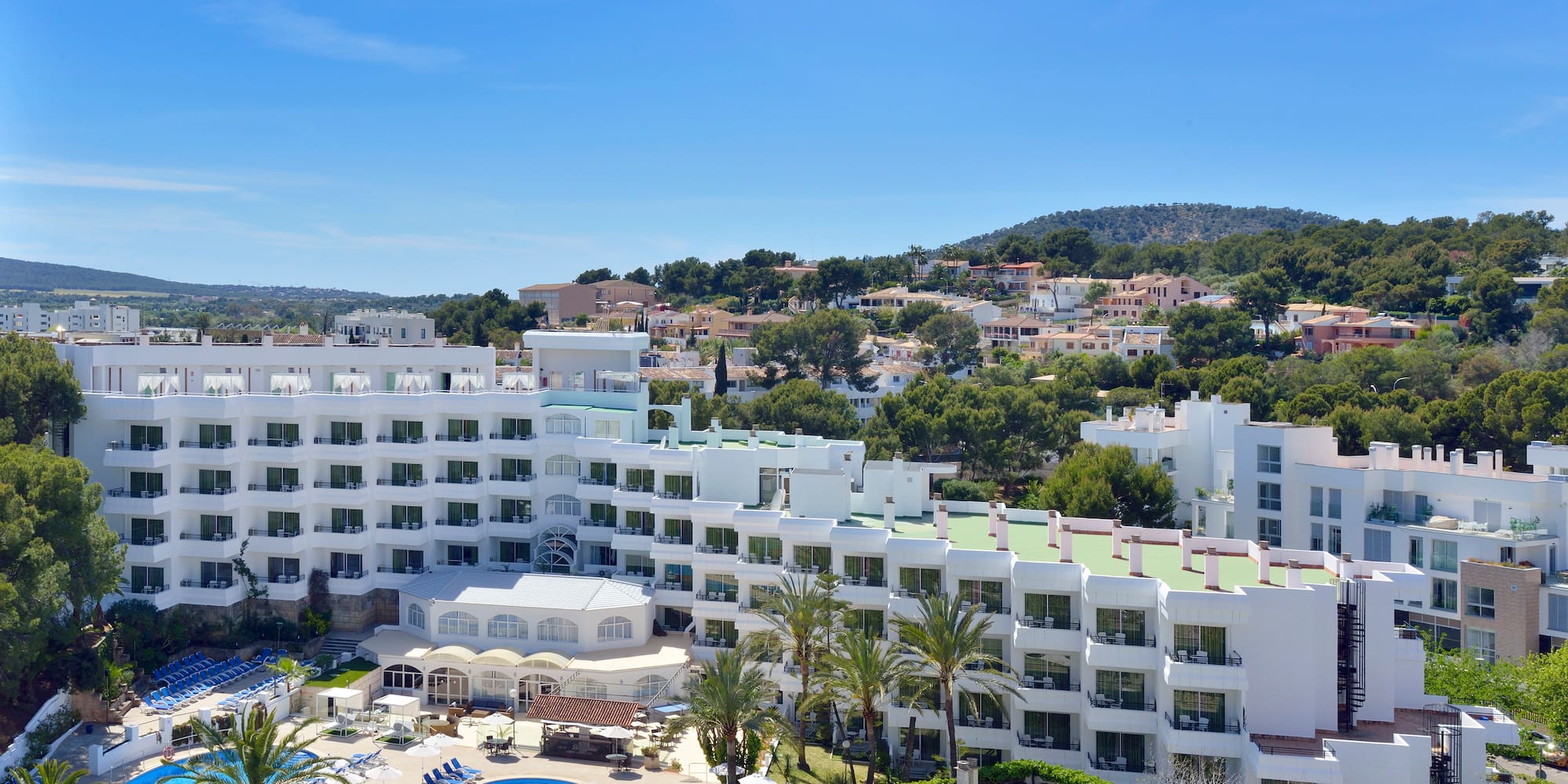 a large white building with a pool and trees in the background