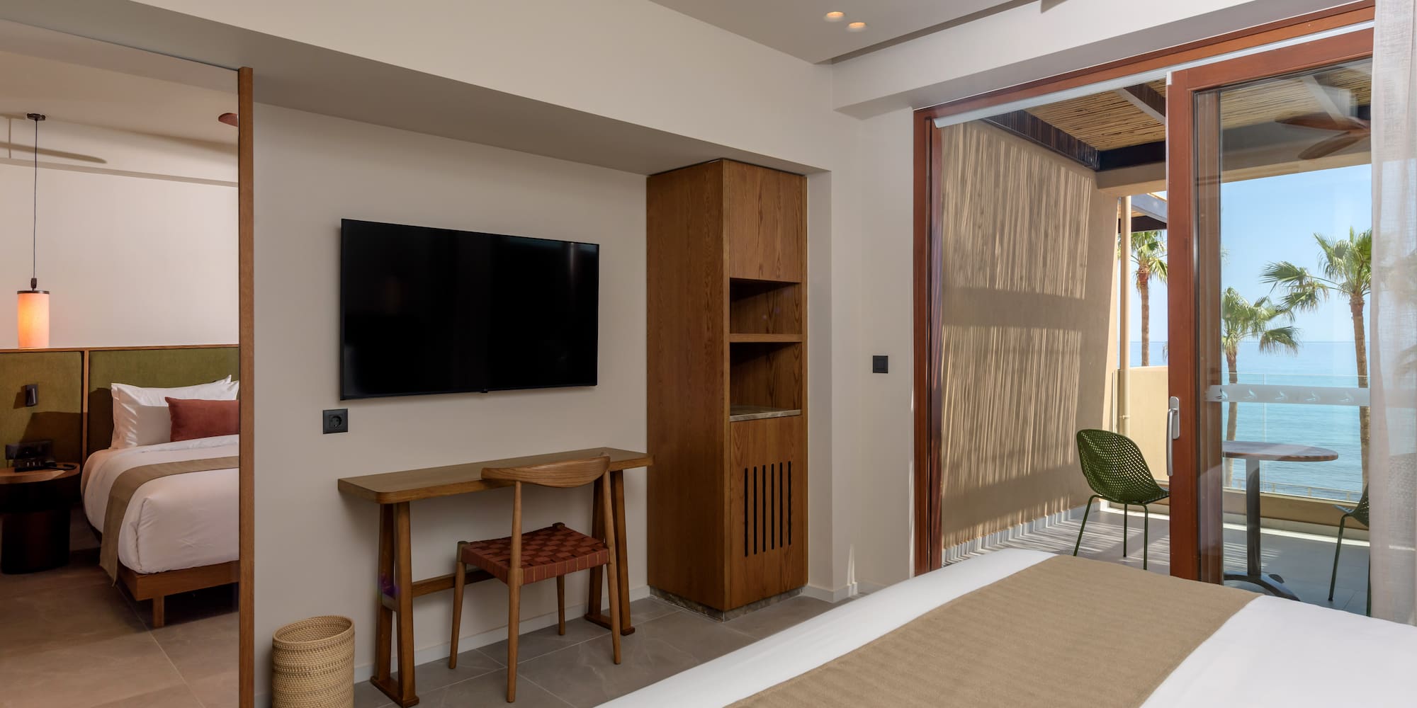 Modern hotel room with ocean view balcony, bed, and desk.