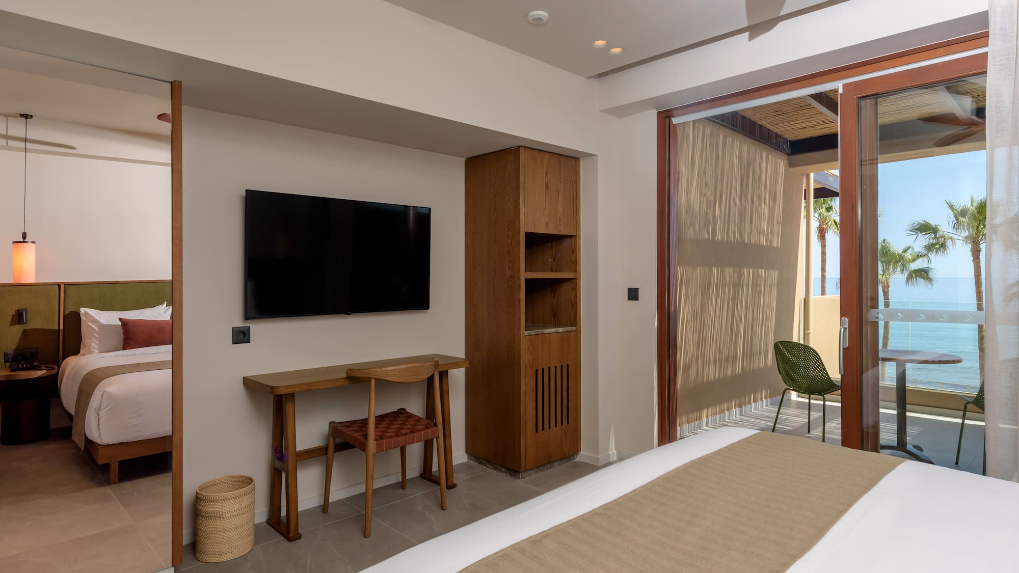 Modern hotel room with ocean view balcony, bed, and desk.
