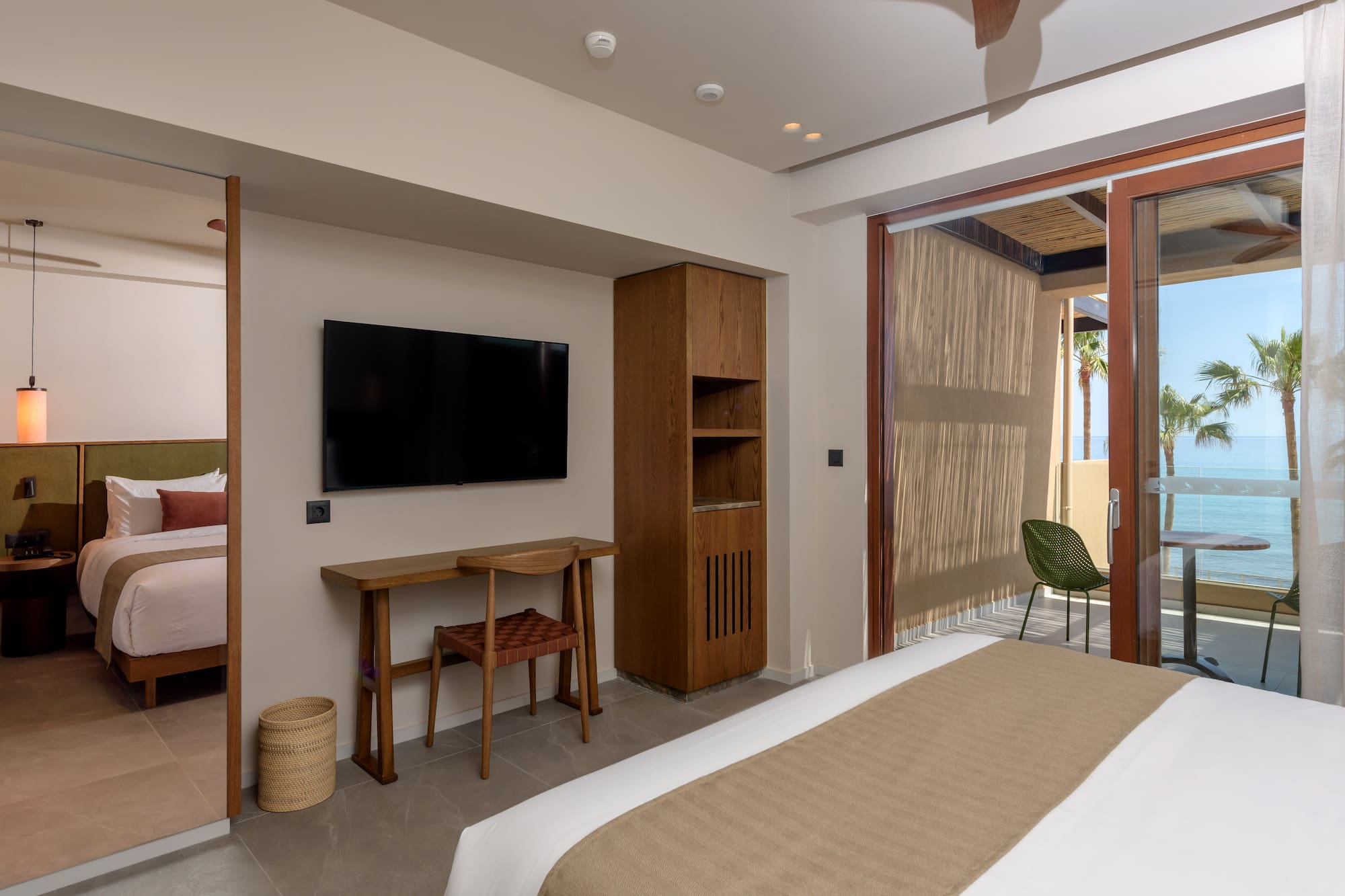 Modern hotel room with ocean view balcony, bed, and desk.