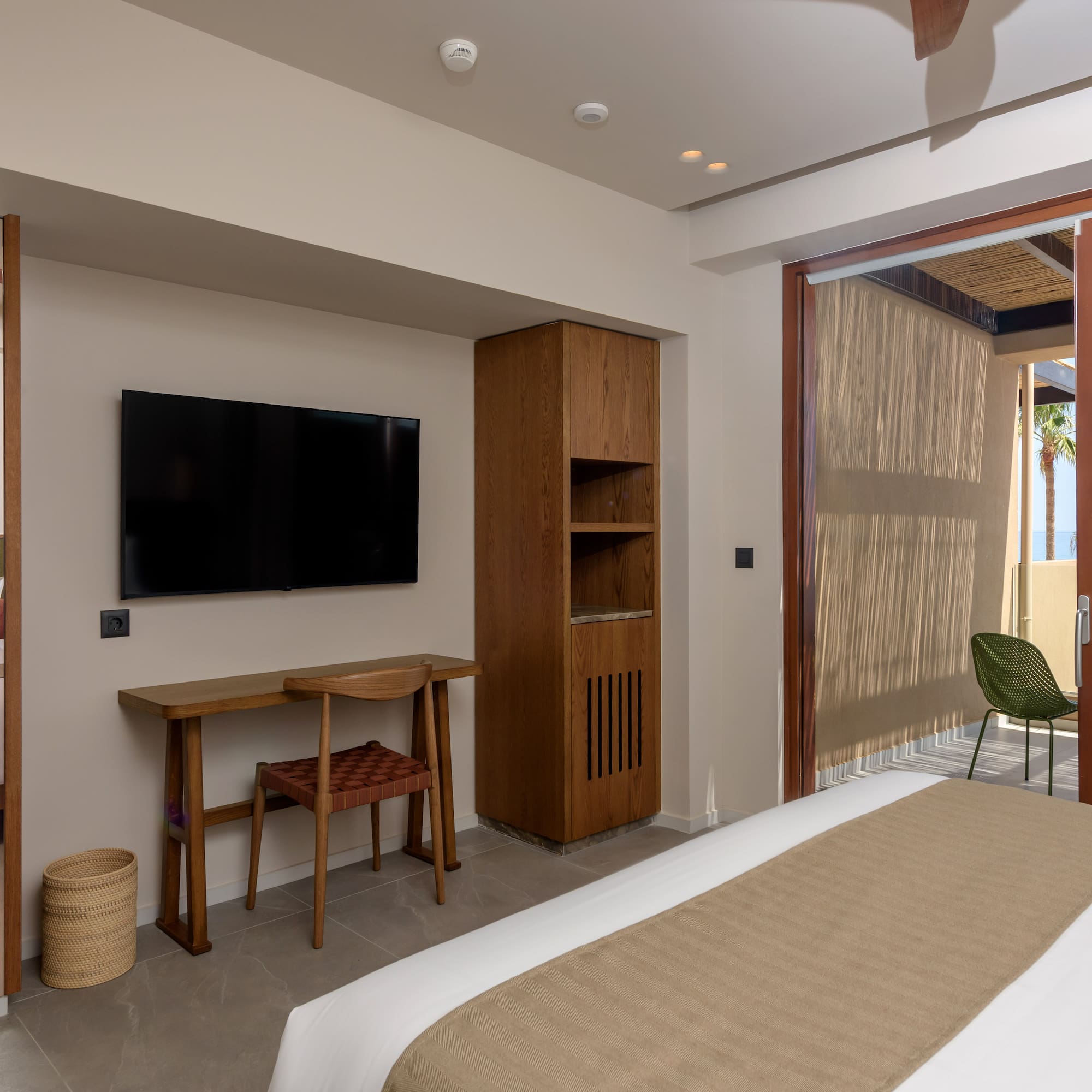 Modern hotel room with ocean view balcony, bed, and desk.