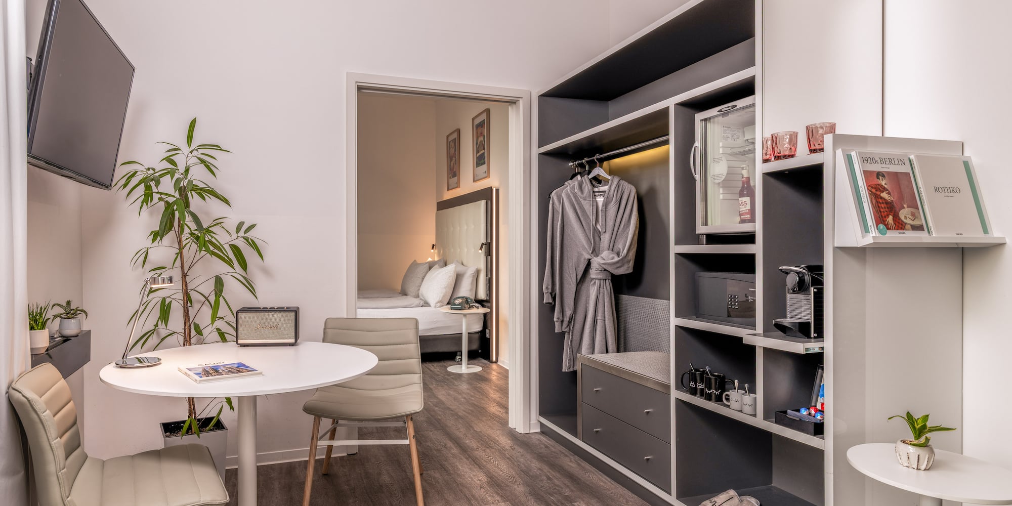 Modern hotel room with living area, bedroom, and built-in wardrobe amenities.