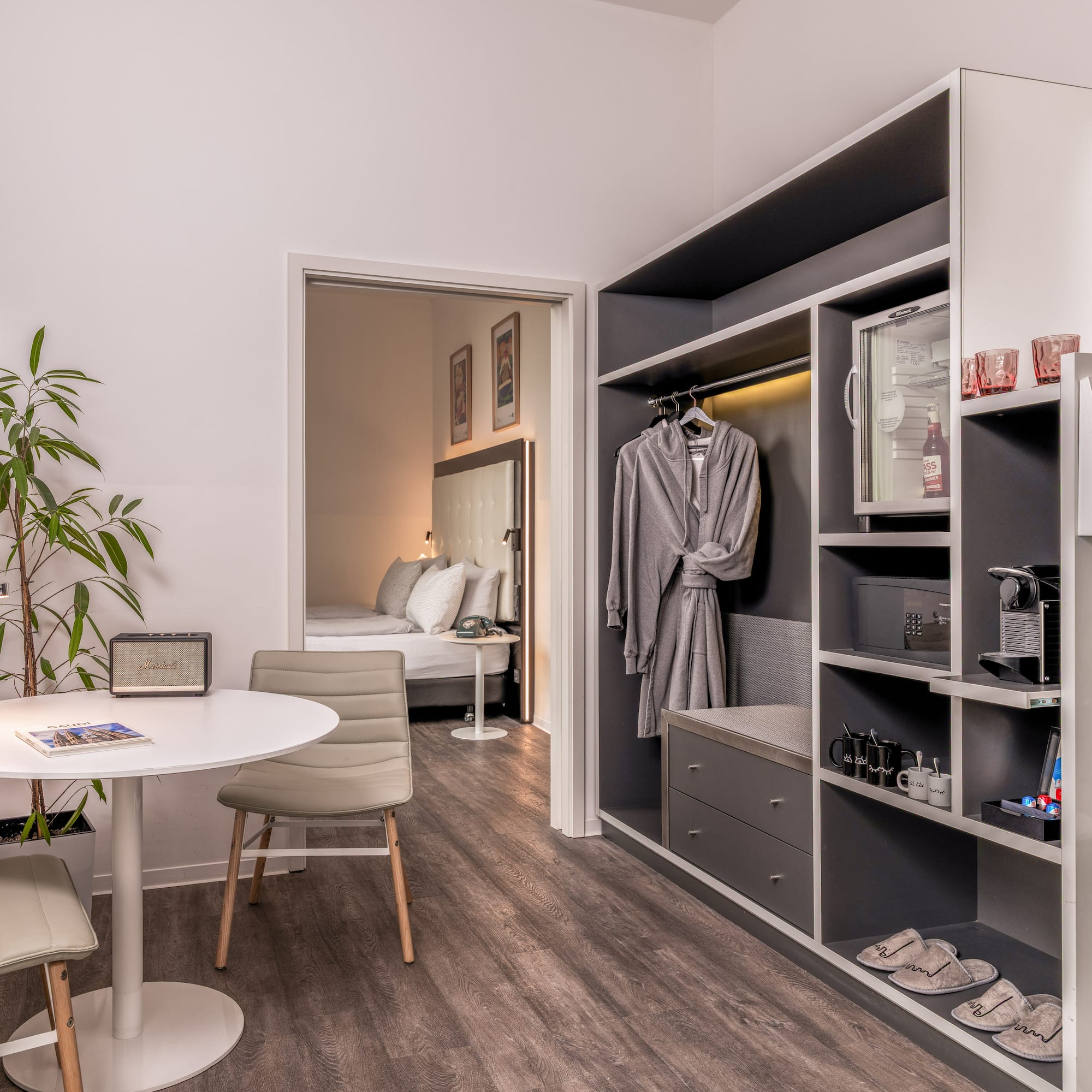 Modern hotel room with living area, bedroom, and built-in wardrobe amenities.