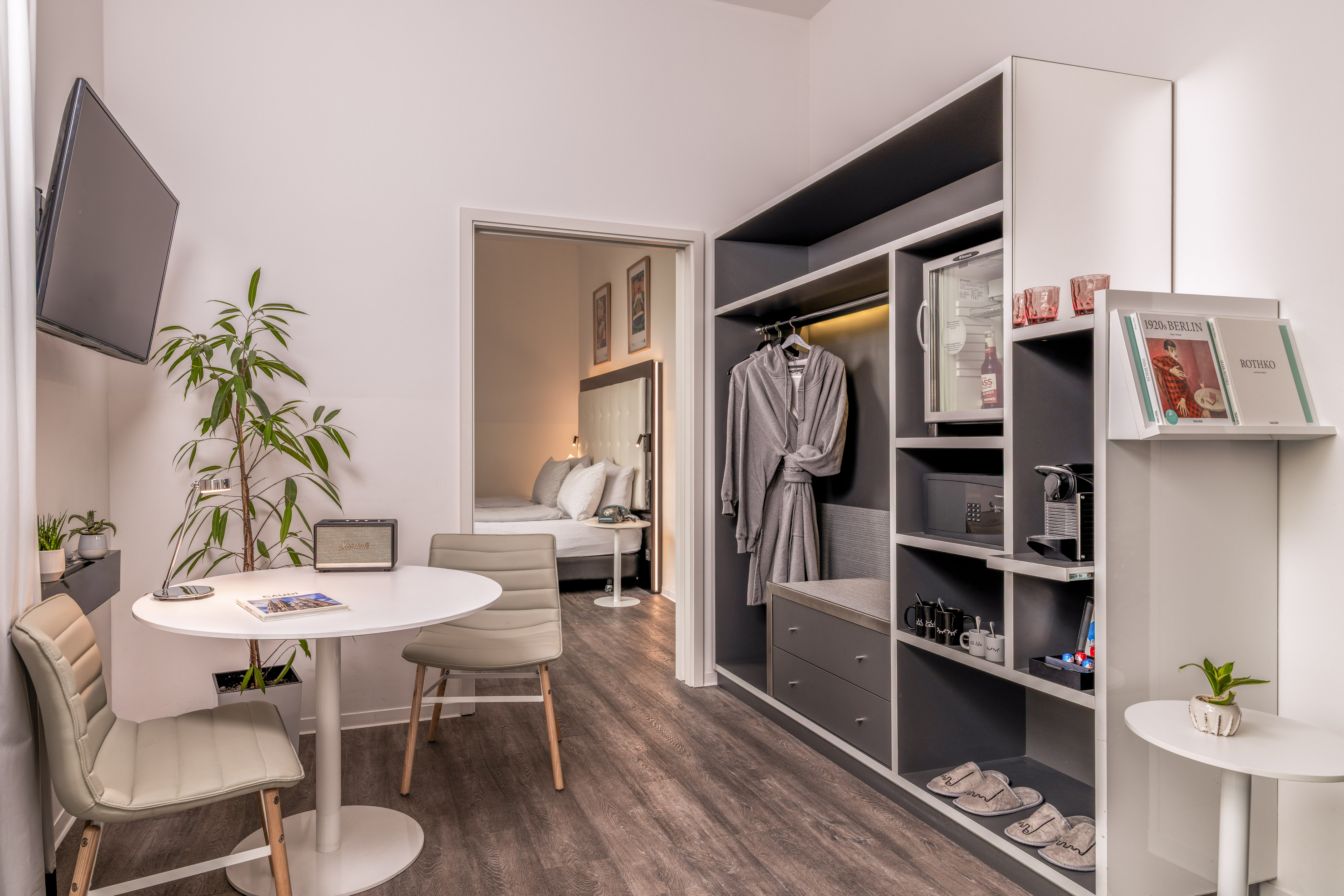 Modern hotel room with living area, bedroom, and built-in wardrobe amenities.