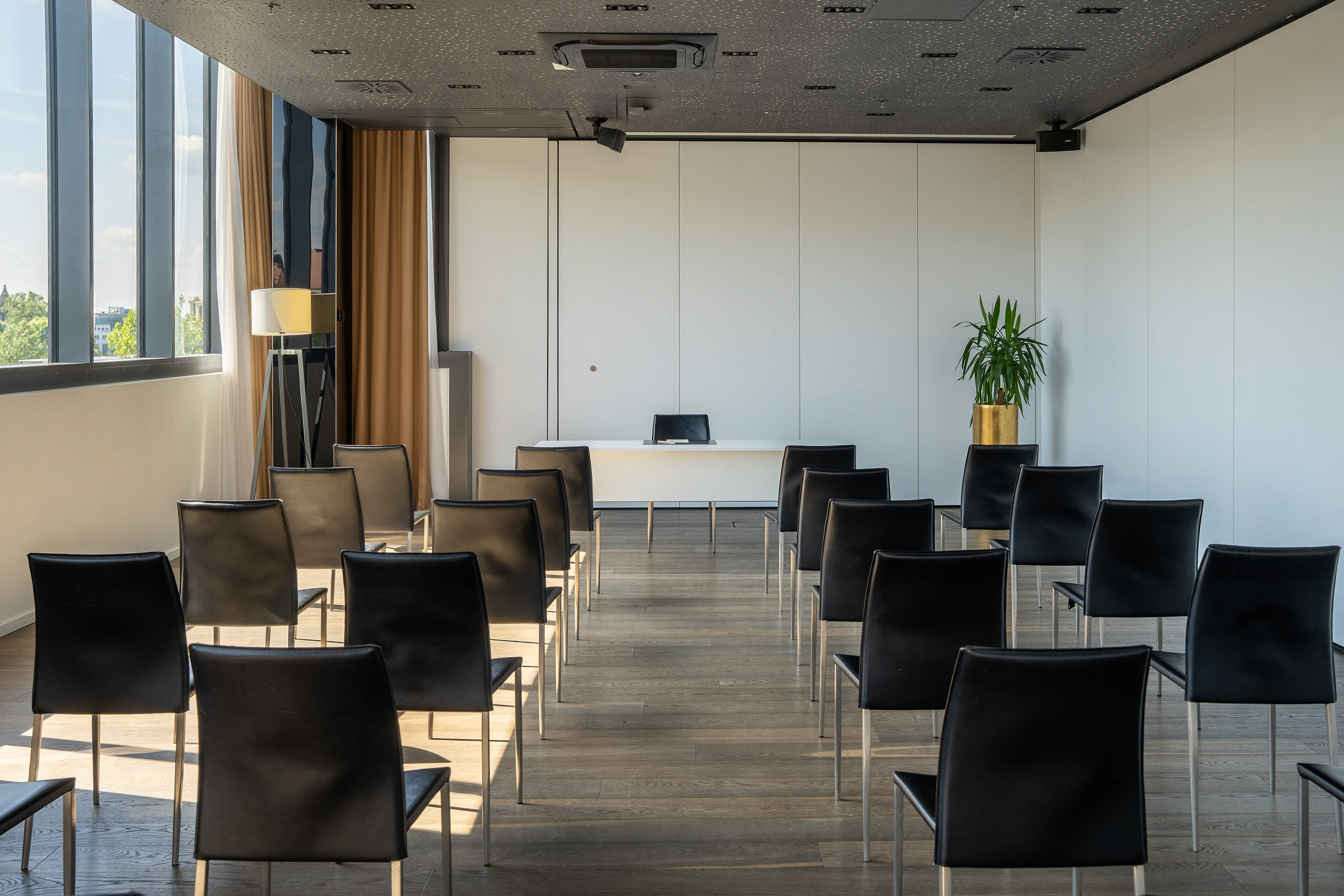 Empty modern conference room with black chairs, presentation desk, and large window.