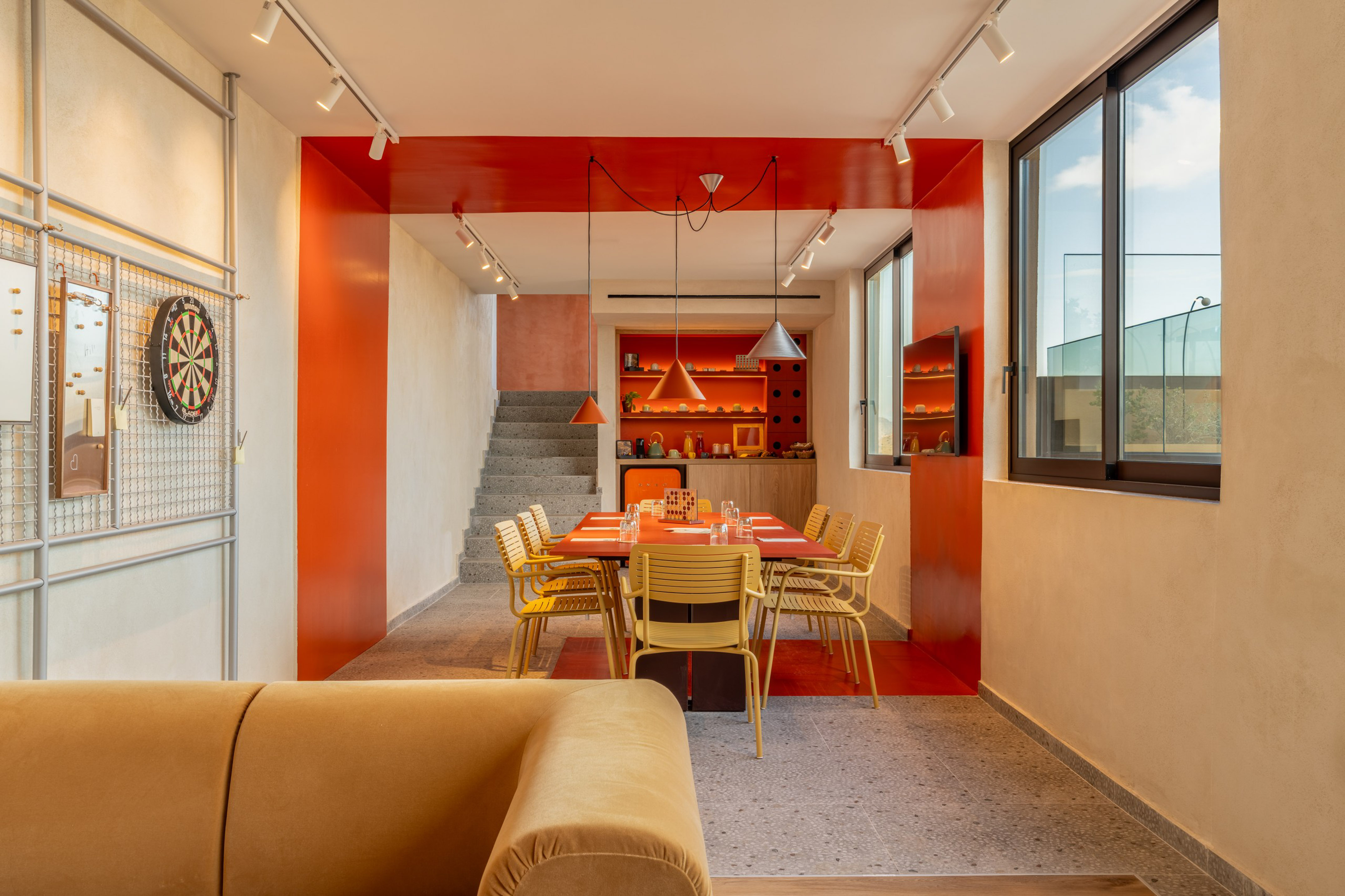 Modern orange & yellow dining room, common area with kitchenette & dartboard.