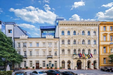 Ornate white hotel building with international flags, cars, and modern architecture.