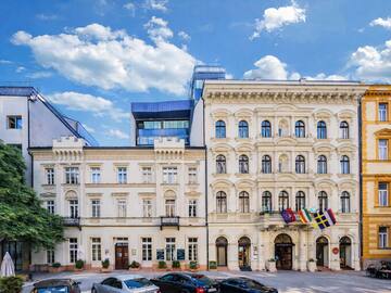 Ornate white hotel building with international flags, cars, and modern architecture.