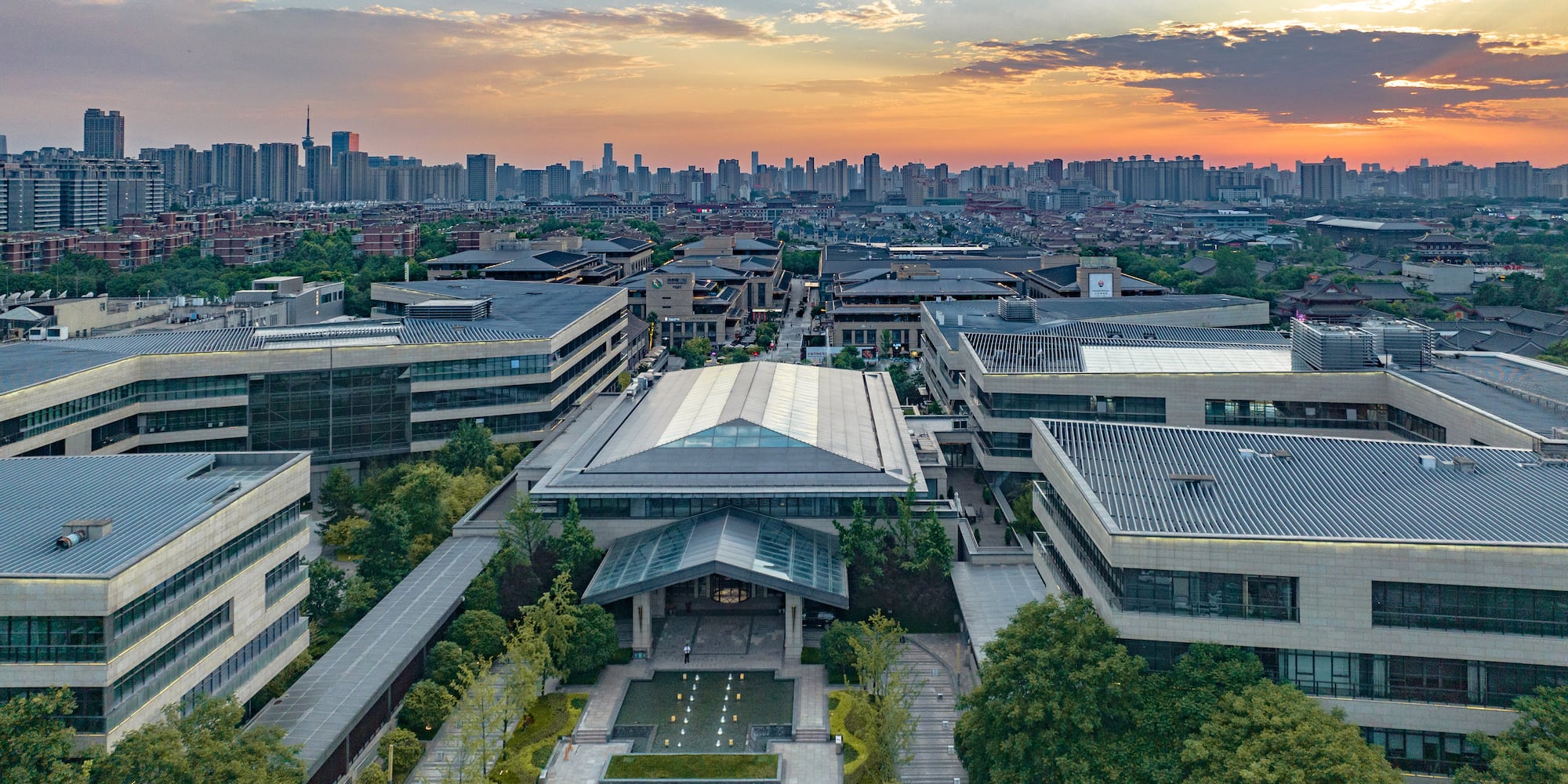 a group of buildings with trees and a city in the background