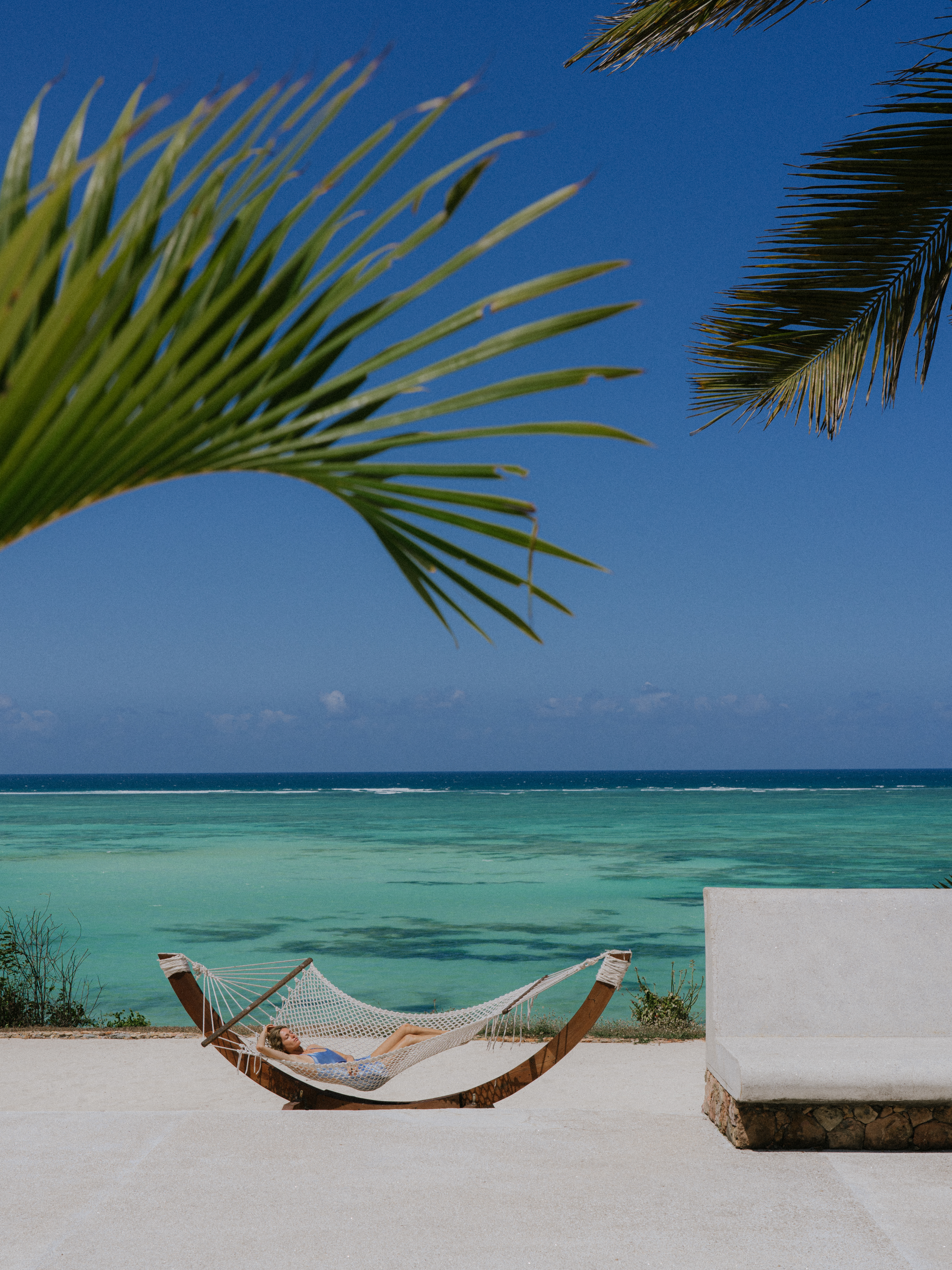 a person lying in a hammock on a beach