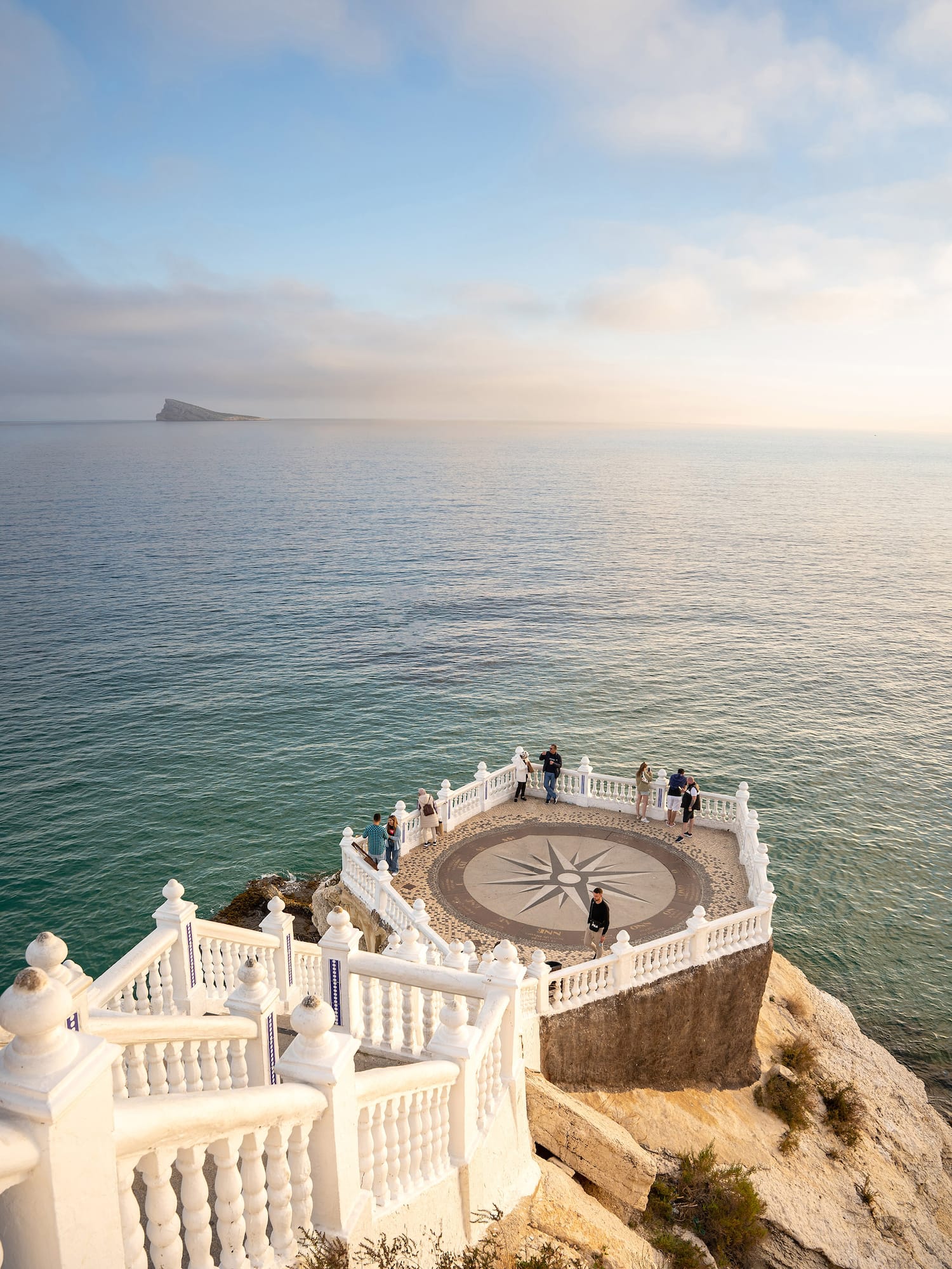 a white railing on a stone ledge overlooking a body of water