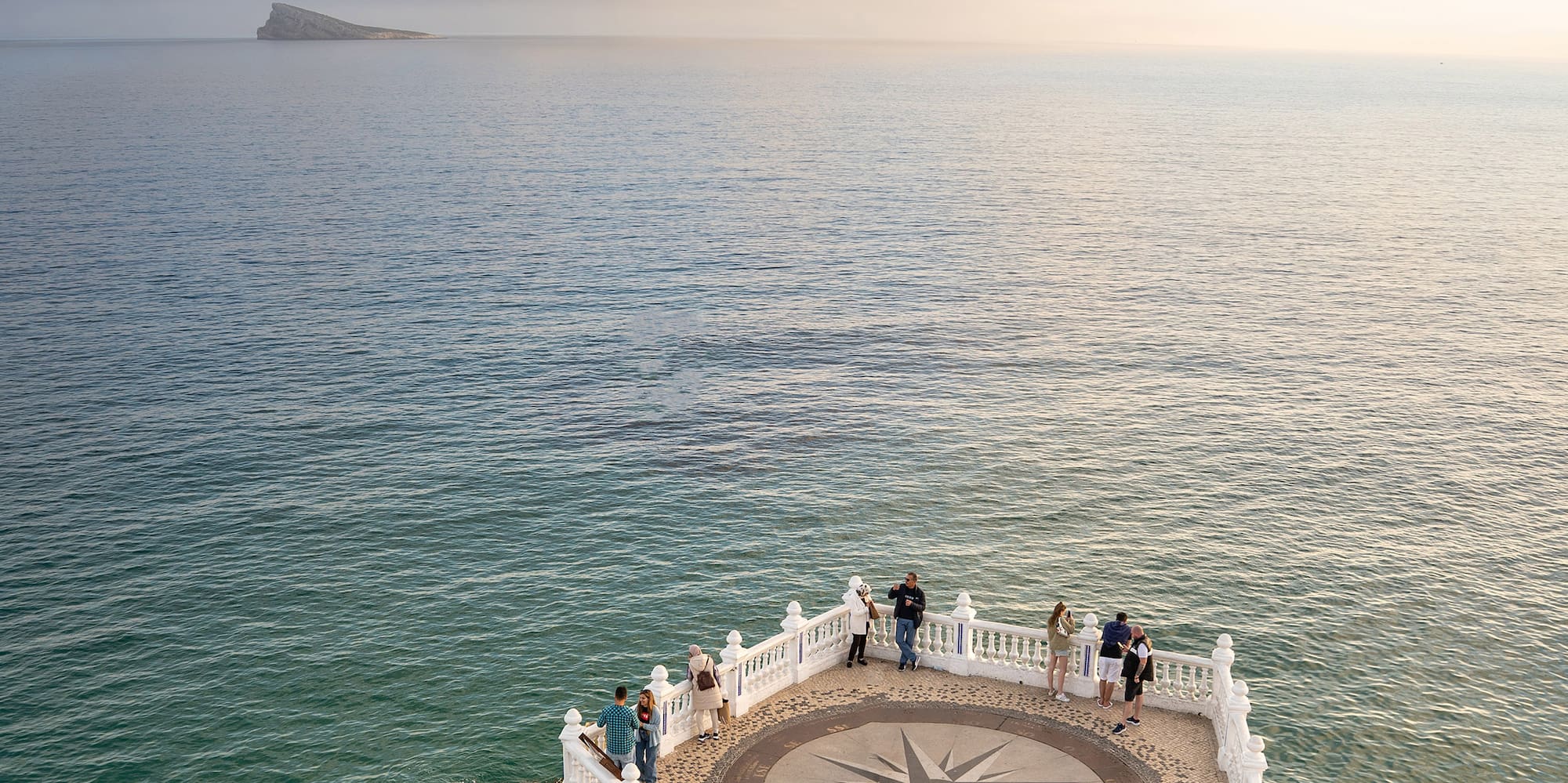 a white railing on a stone ledge overlooking a body of water