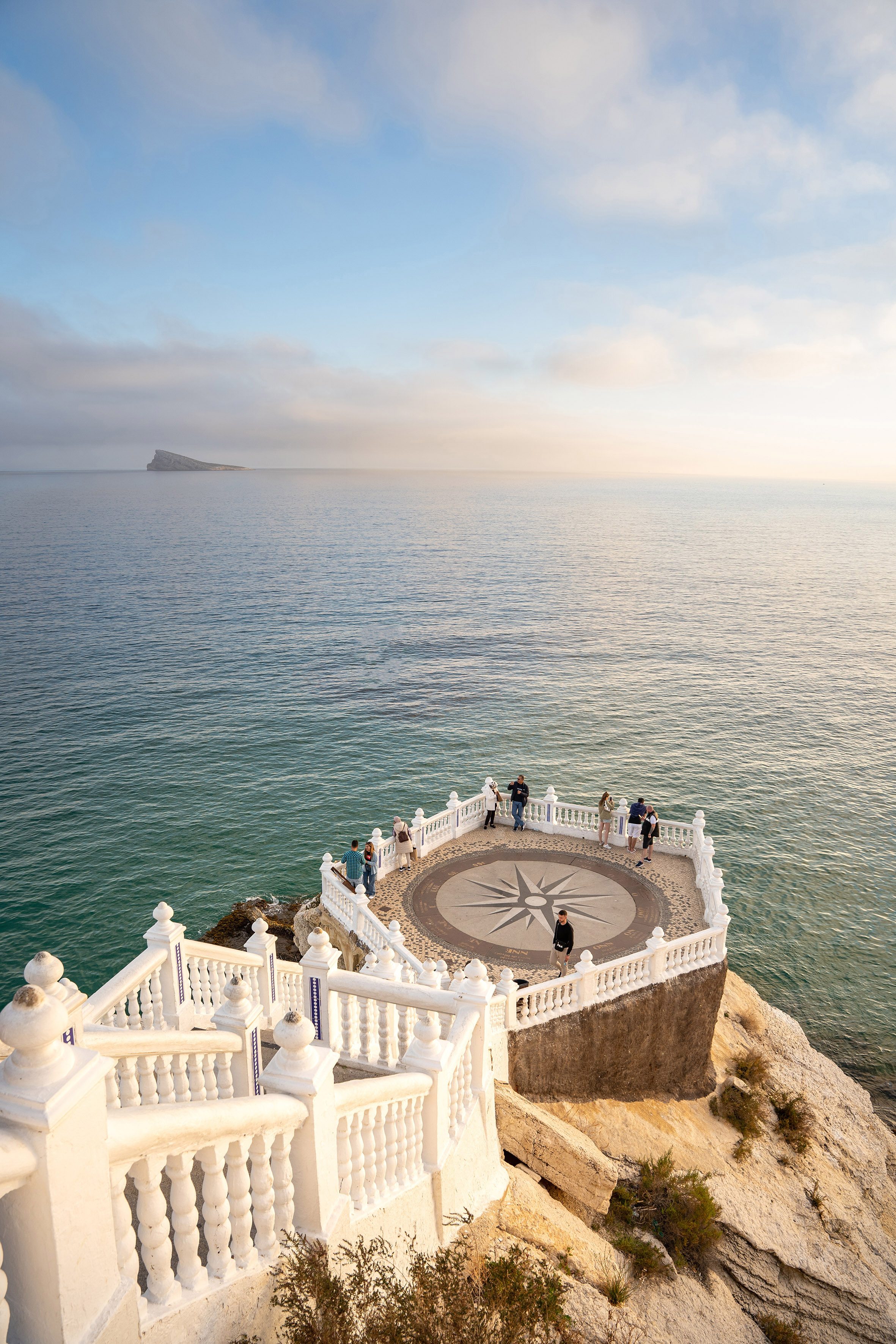 a white railing on a stone ledge overlooking a body of water