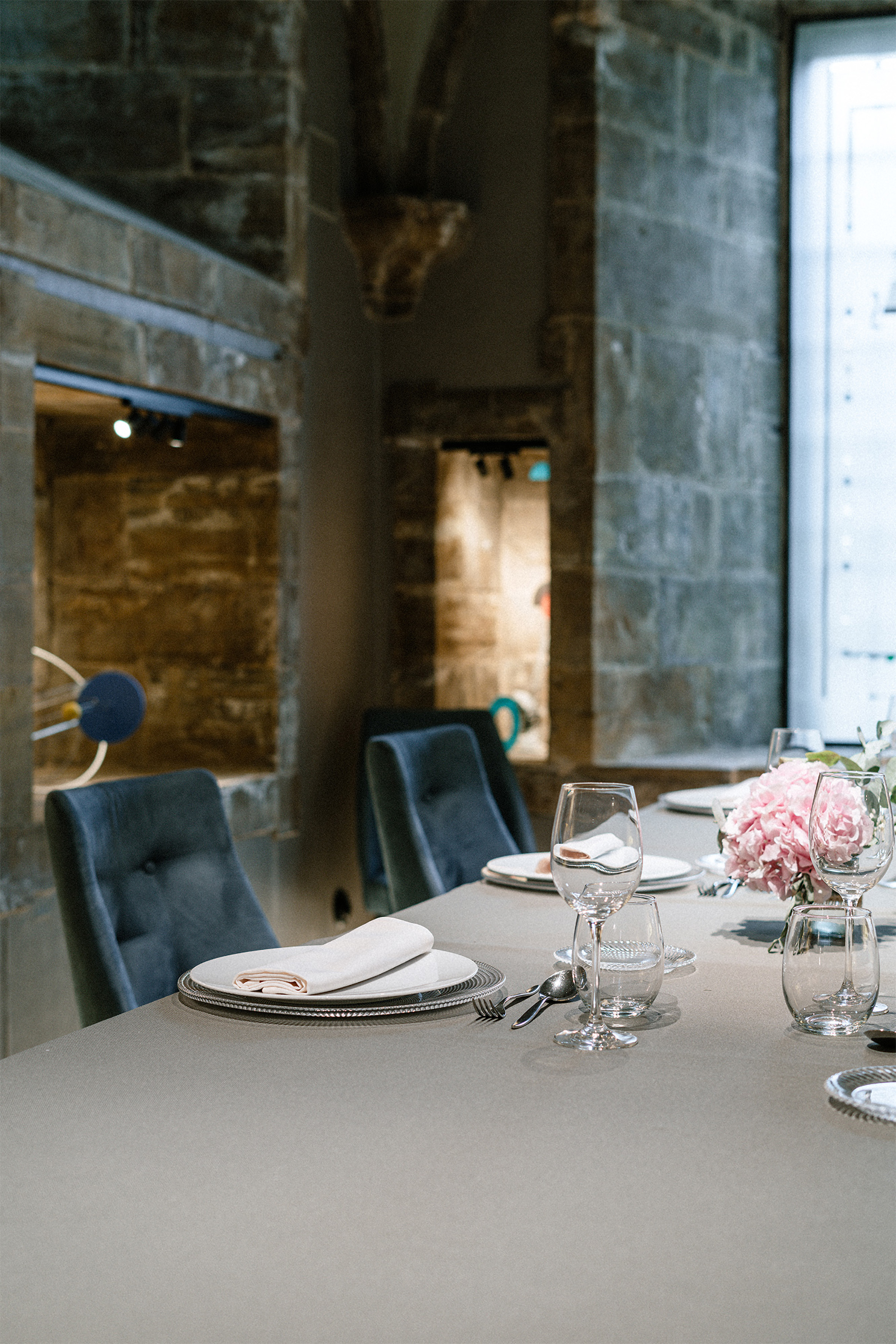 Elegant dining table with pink flowers, velvet chairs, historic stone restaurant. - Archivo - Palacio de Avilés Afiliat Meliá, Avilés