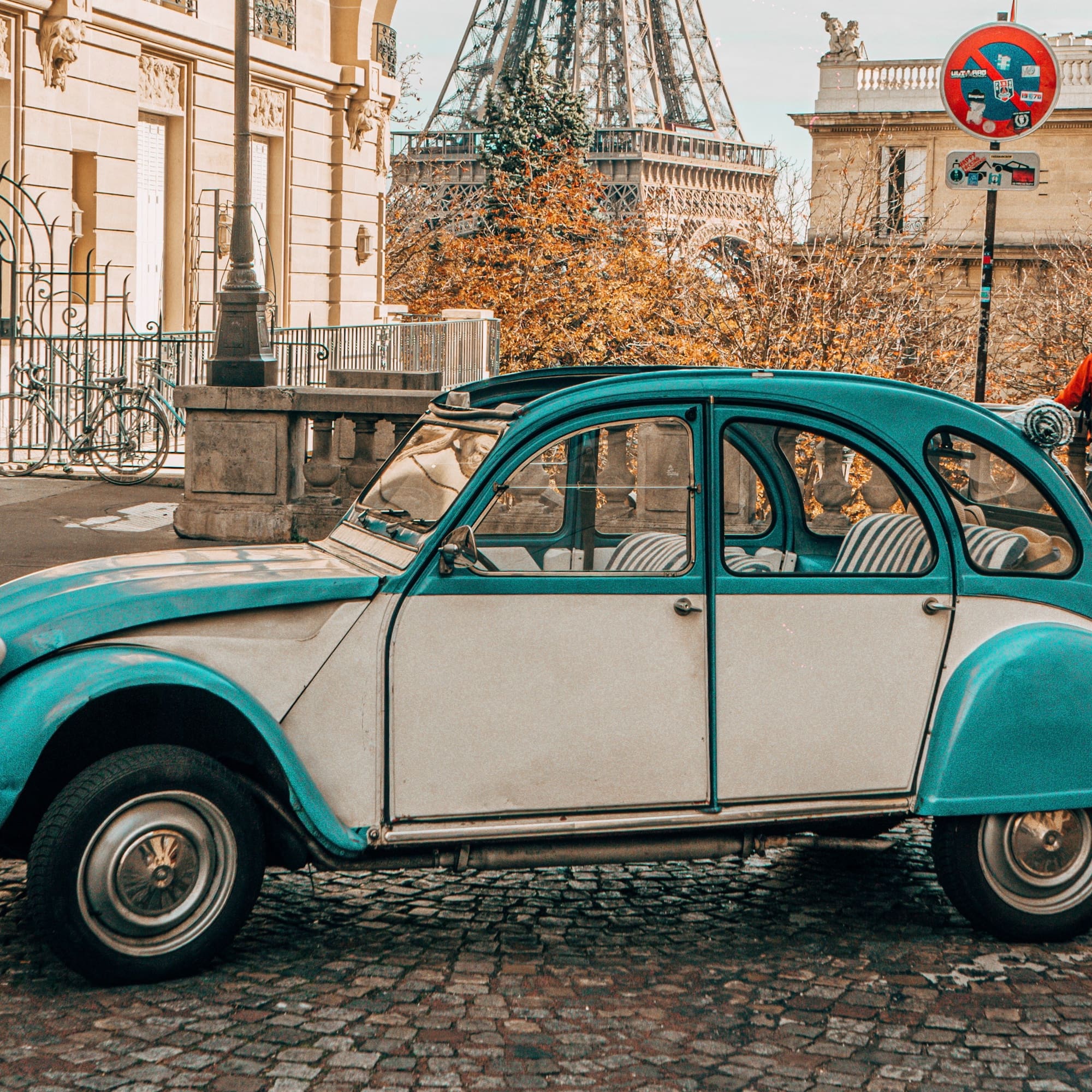 a blue and white car on a cobblestone street