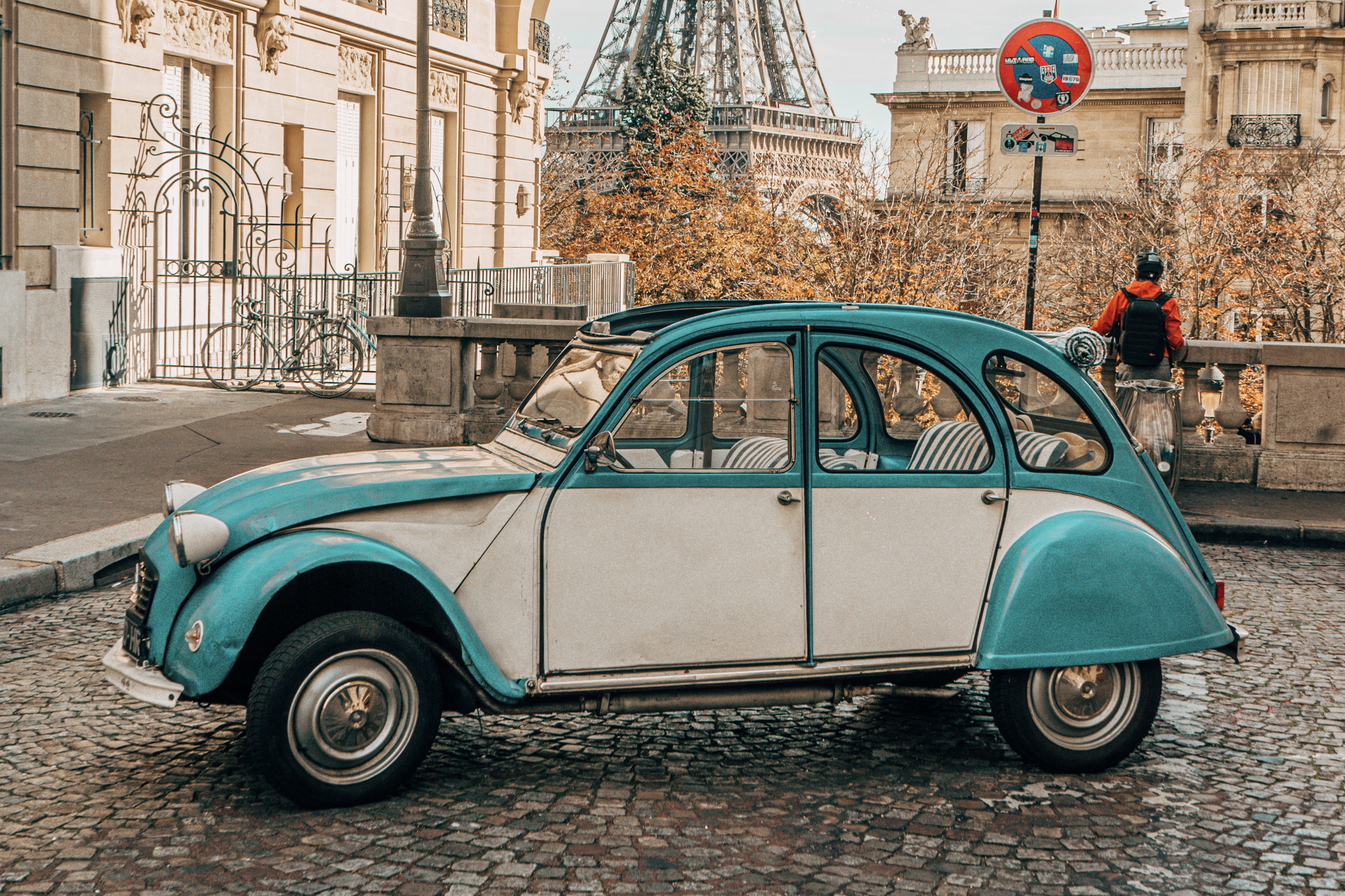 a blue and white car on a cobblestone street