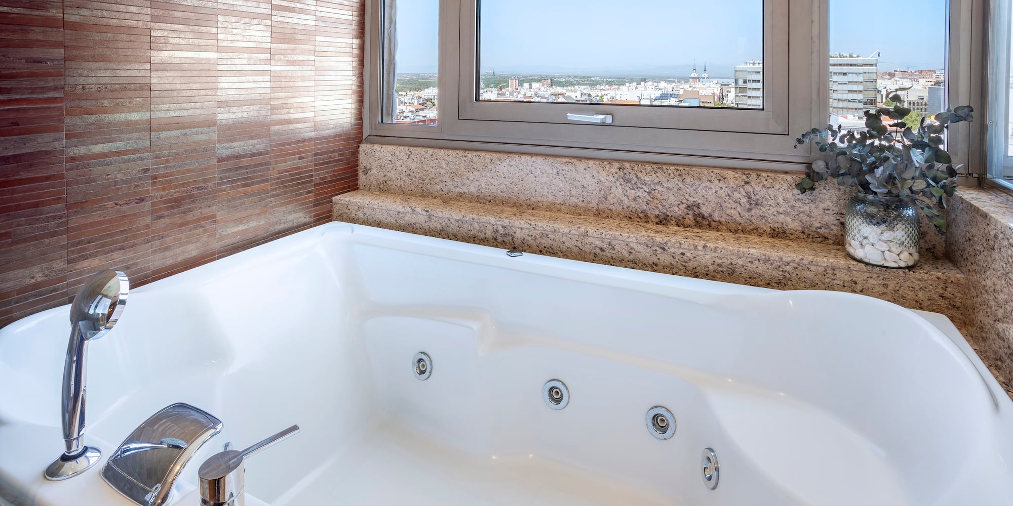 a bathtub with a window and a view of the city