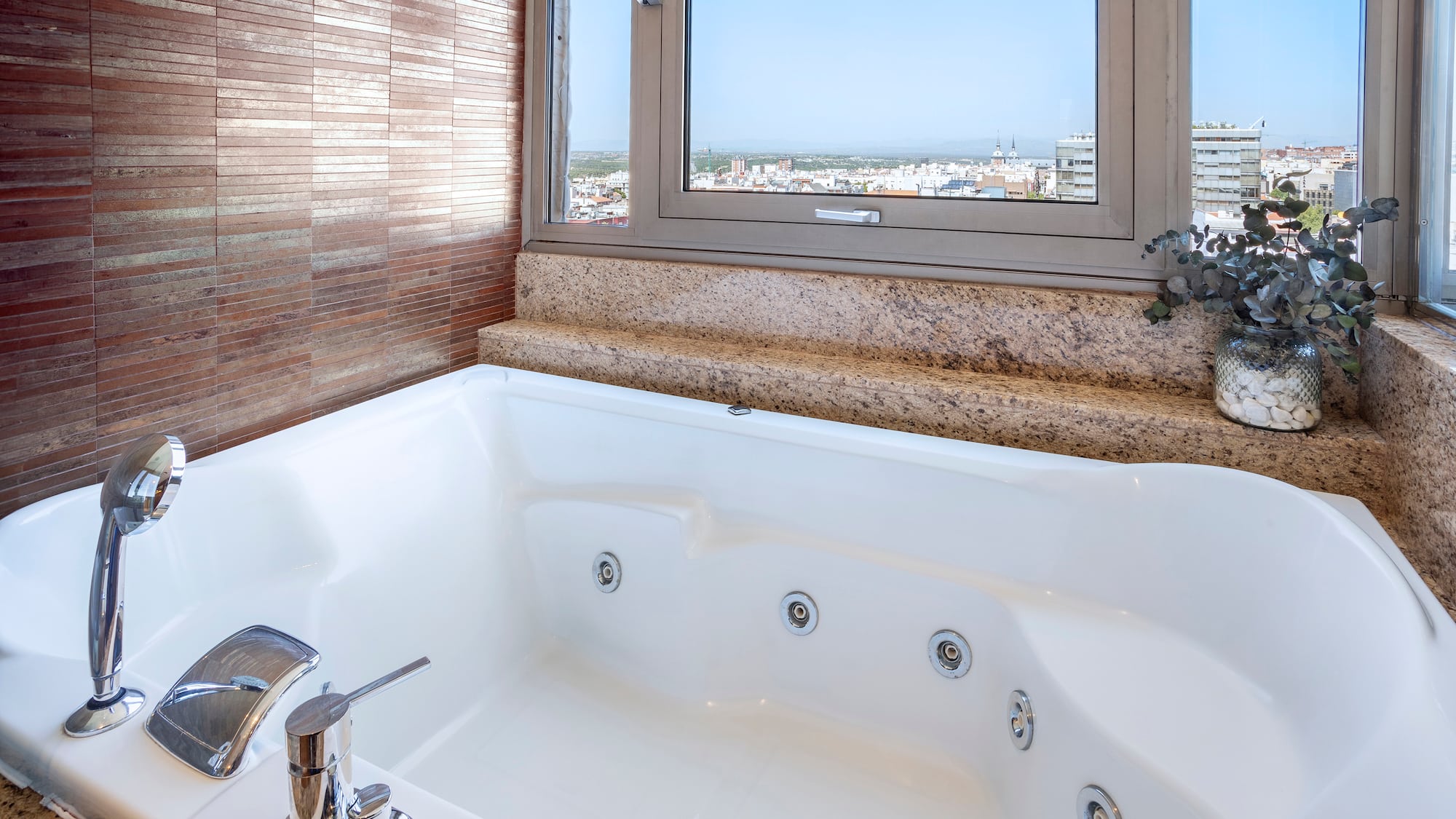 a bathtub with a window and a view of the city