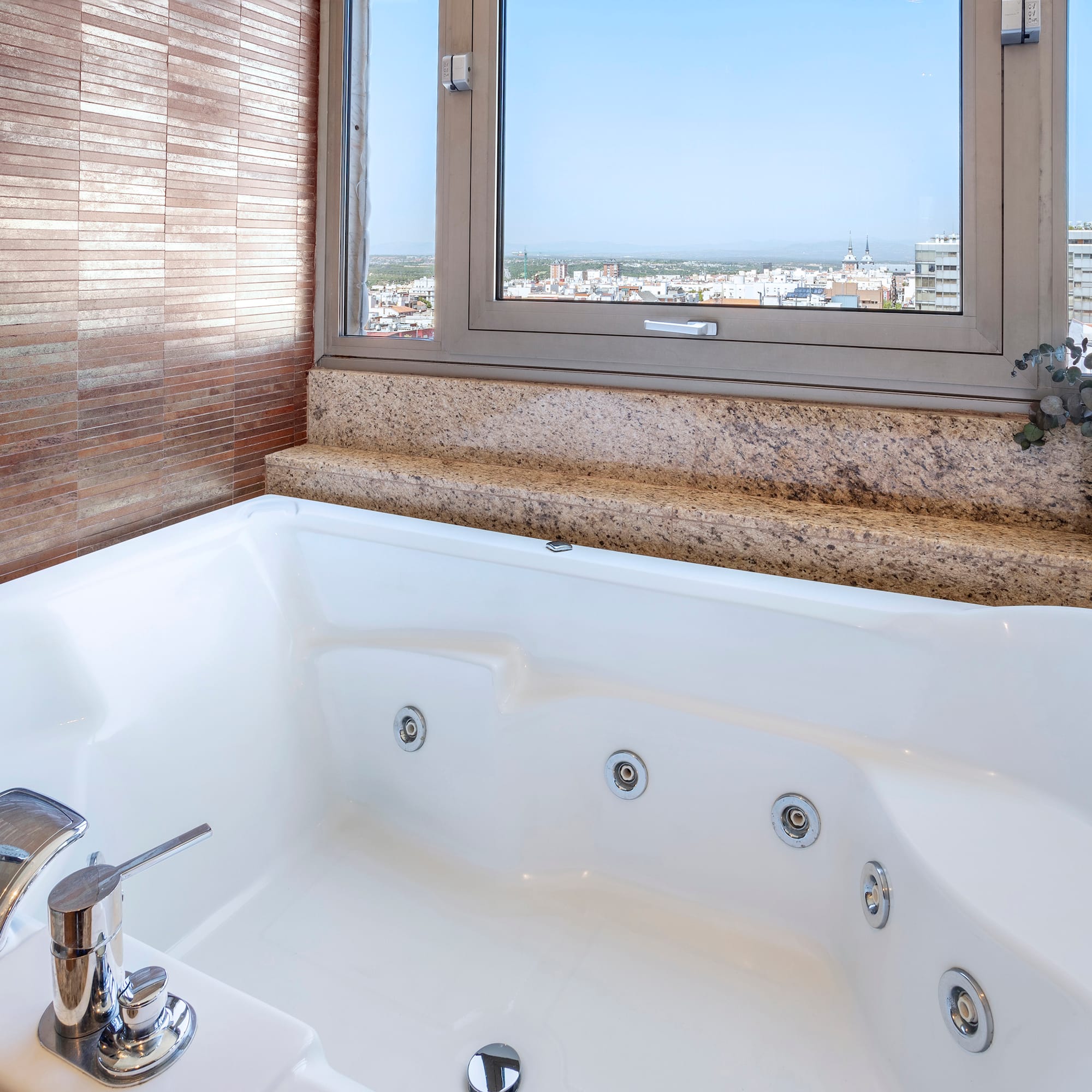 a bathtub with a window and a view of the city