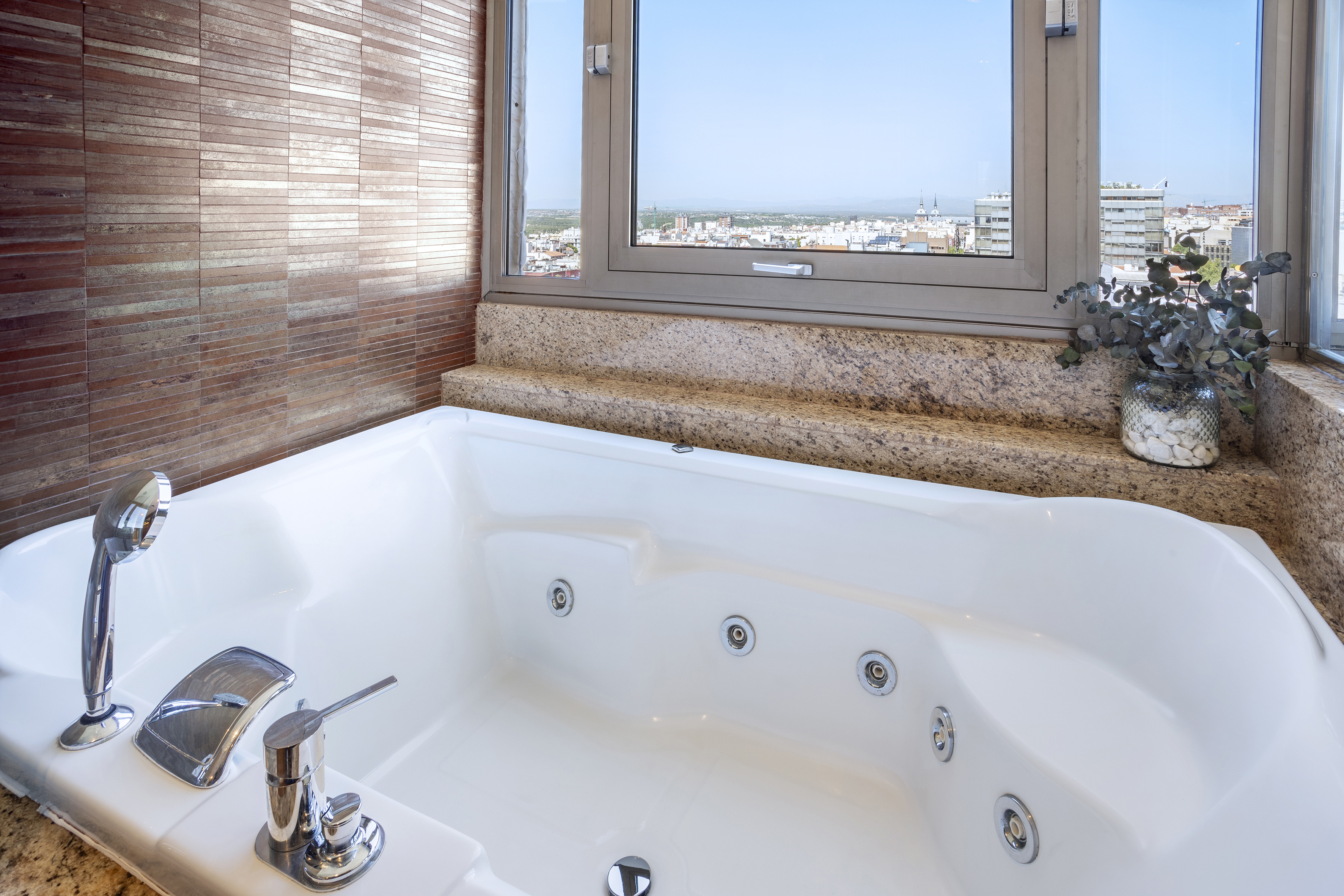 a bathtub with a window and a view of the city