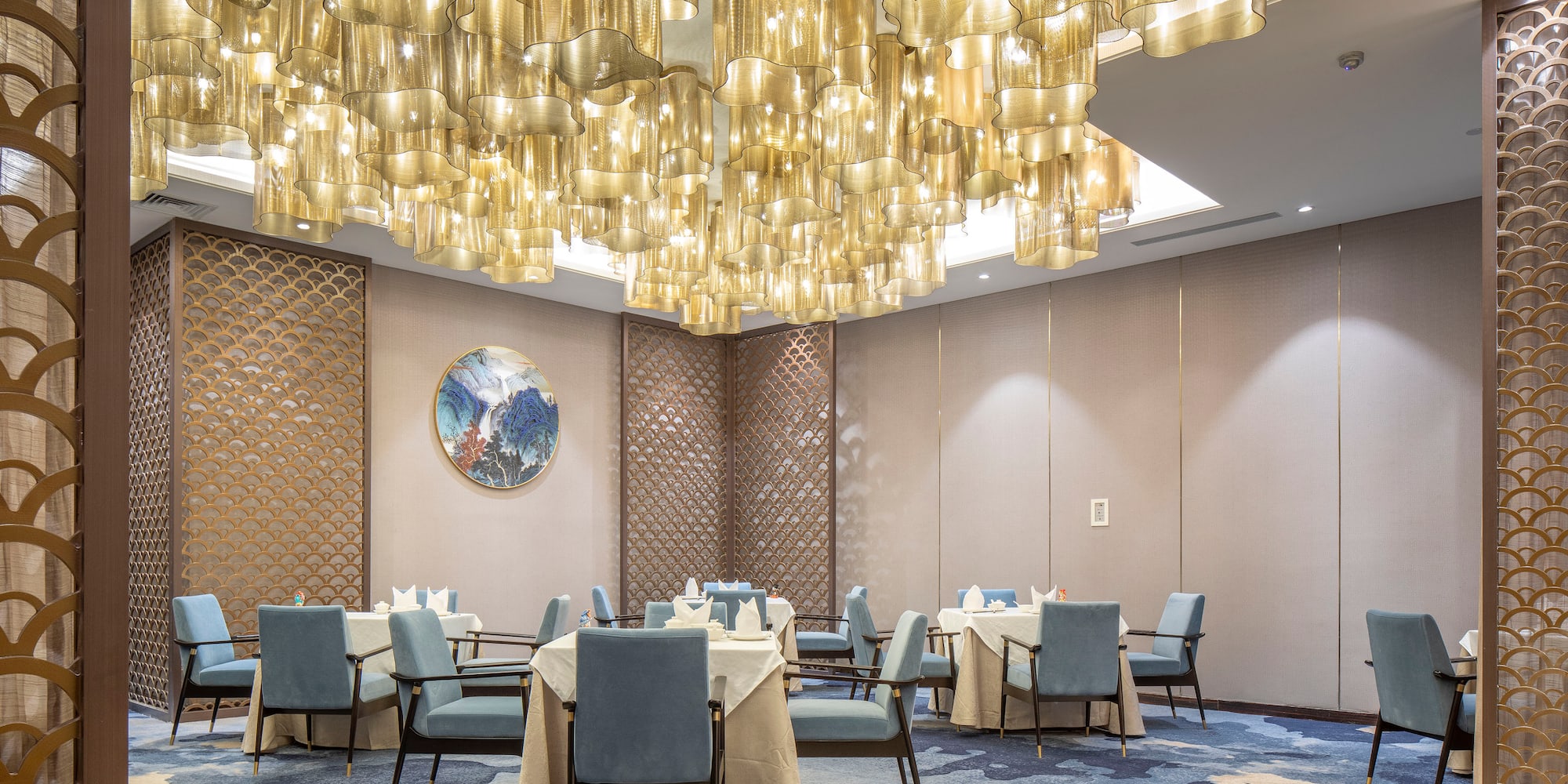 a room with a chandelier and tables and chairs