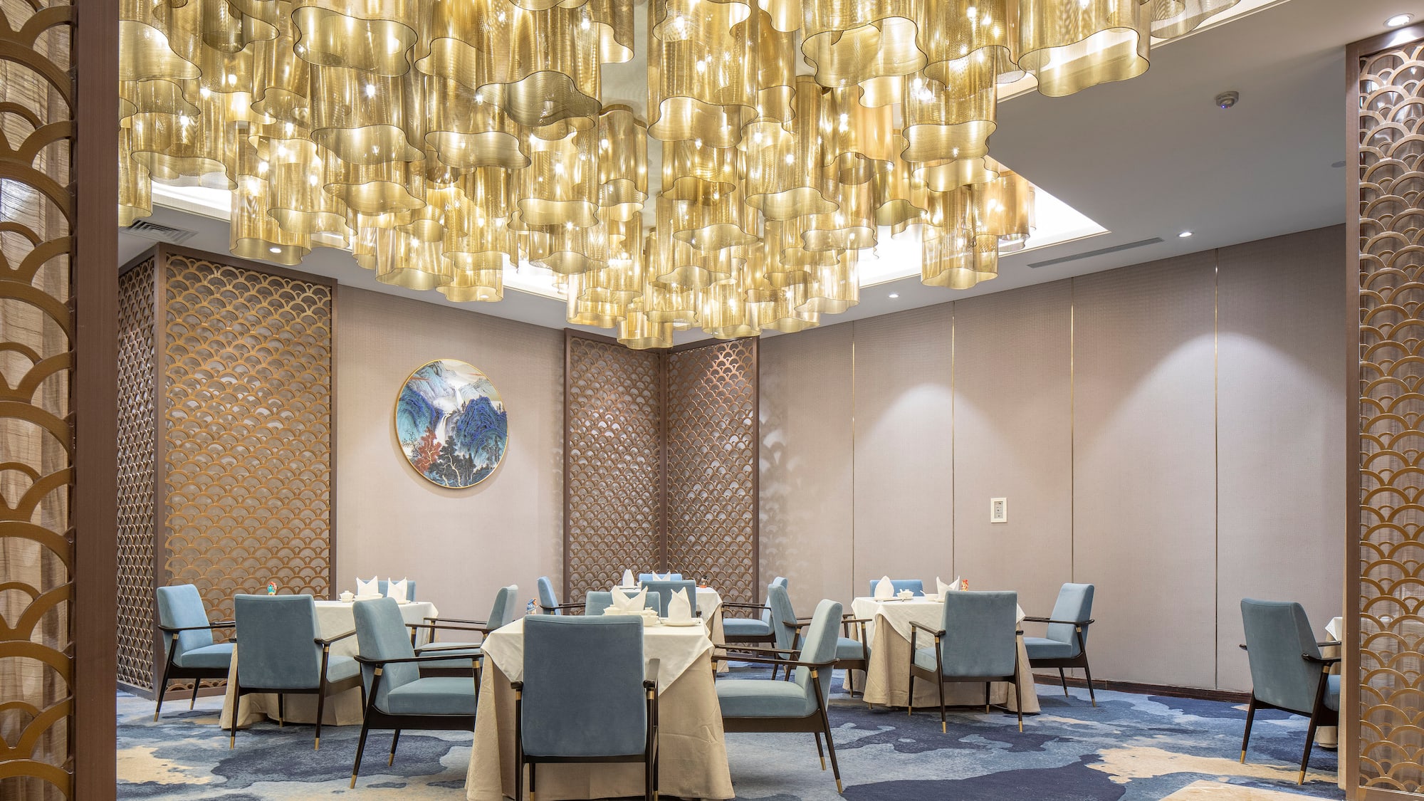 a room with a chandelier and tables and chairs