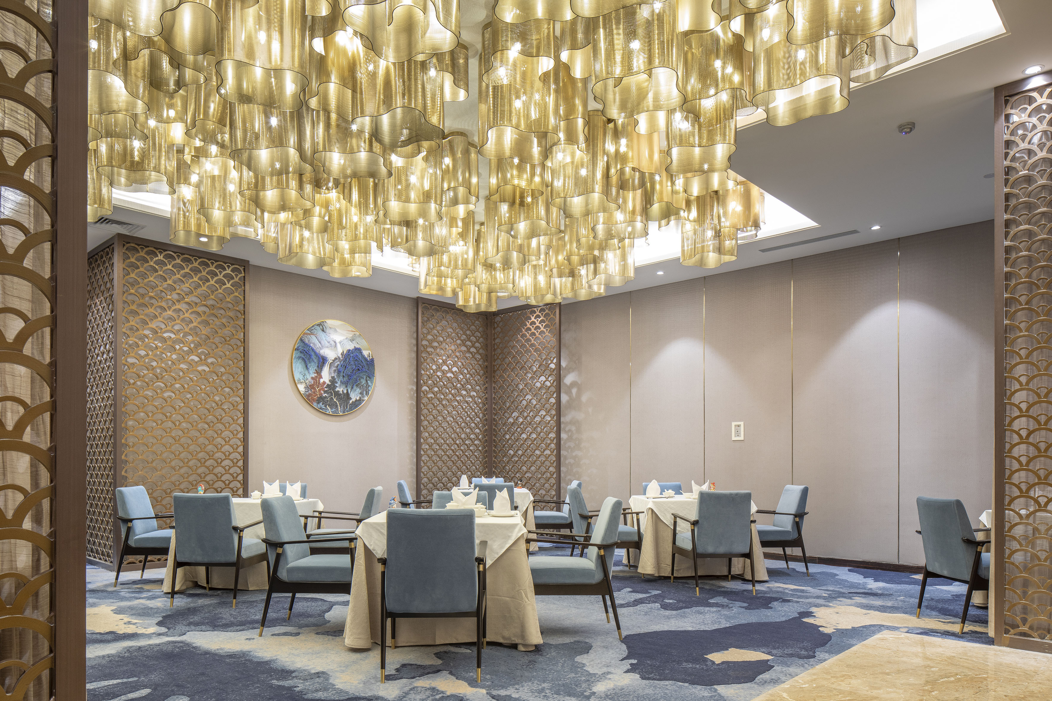 Upscale dining room with golden chandelier lights and blue upholstered chairs.