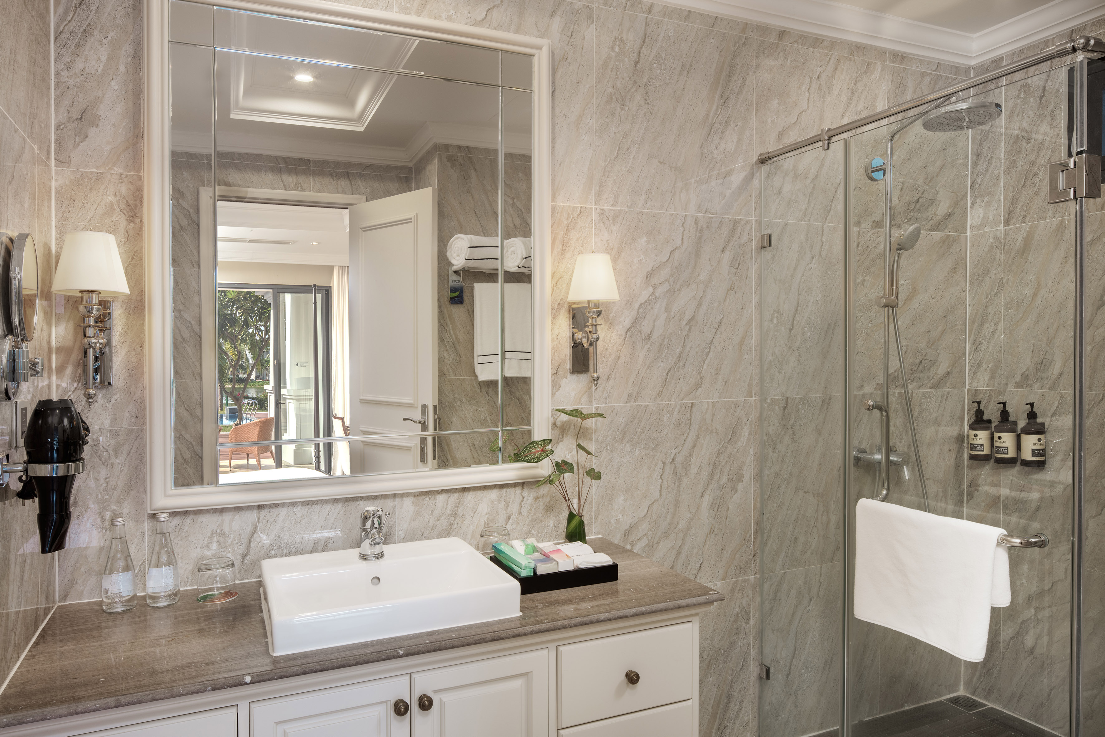 Modern grey bathroom with vanity, vessel sink, glass shower, and large mirror.