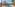 Resort swimming pool with blue water, palm trees, and sun loungers.